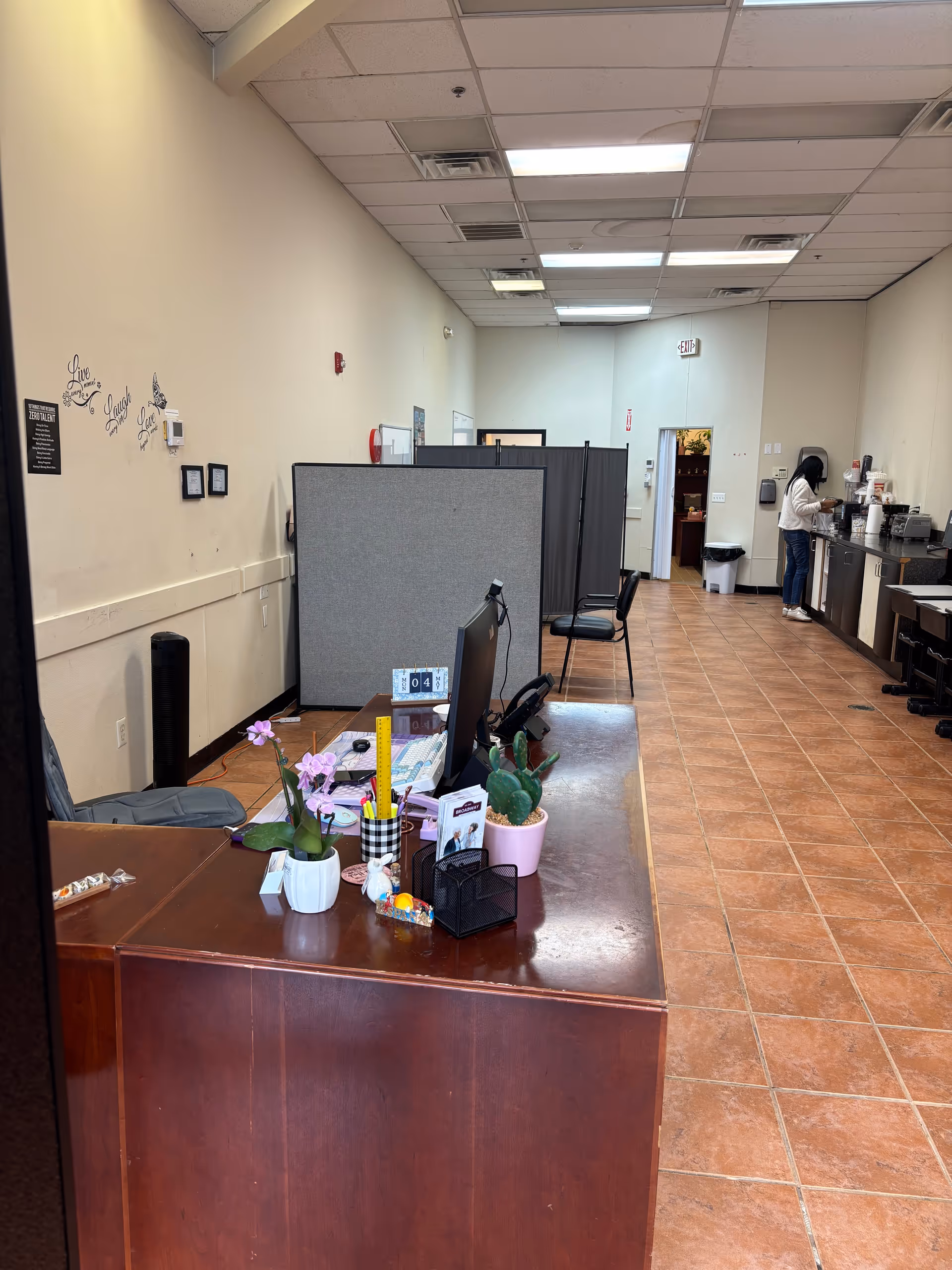 Interior reception area of a senior care facility with a desk, computer, and plants.
