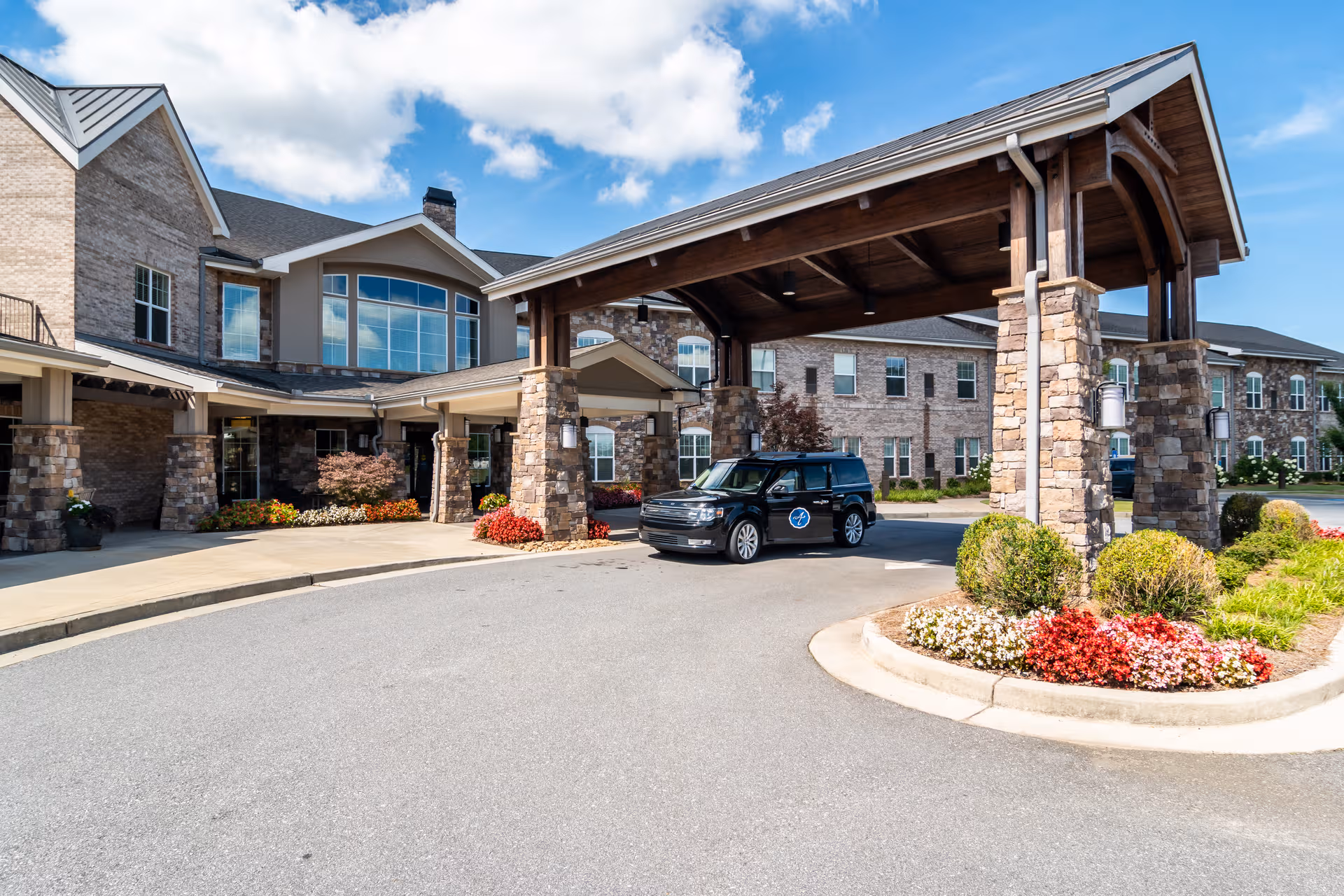 Exterior view of Arbor Terrace Hamilton Mill entrance with stone pillars and a covered drive