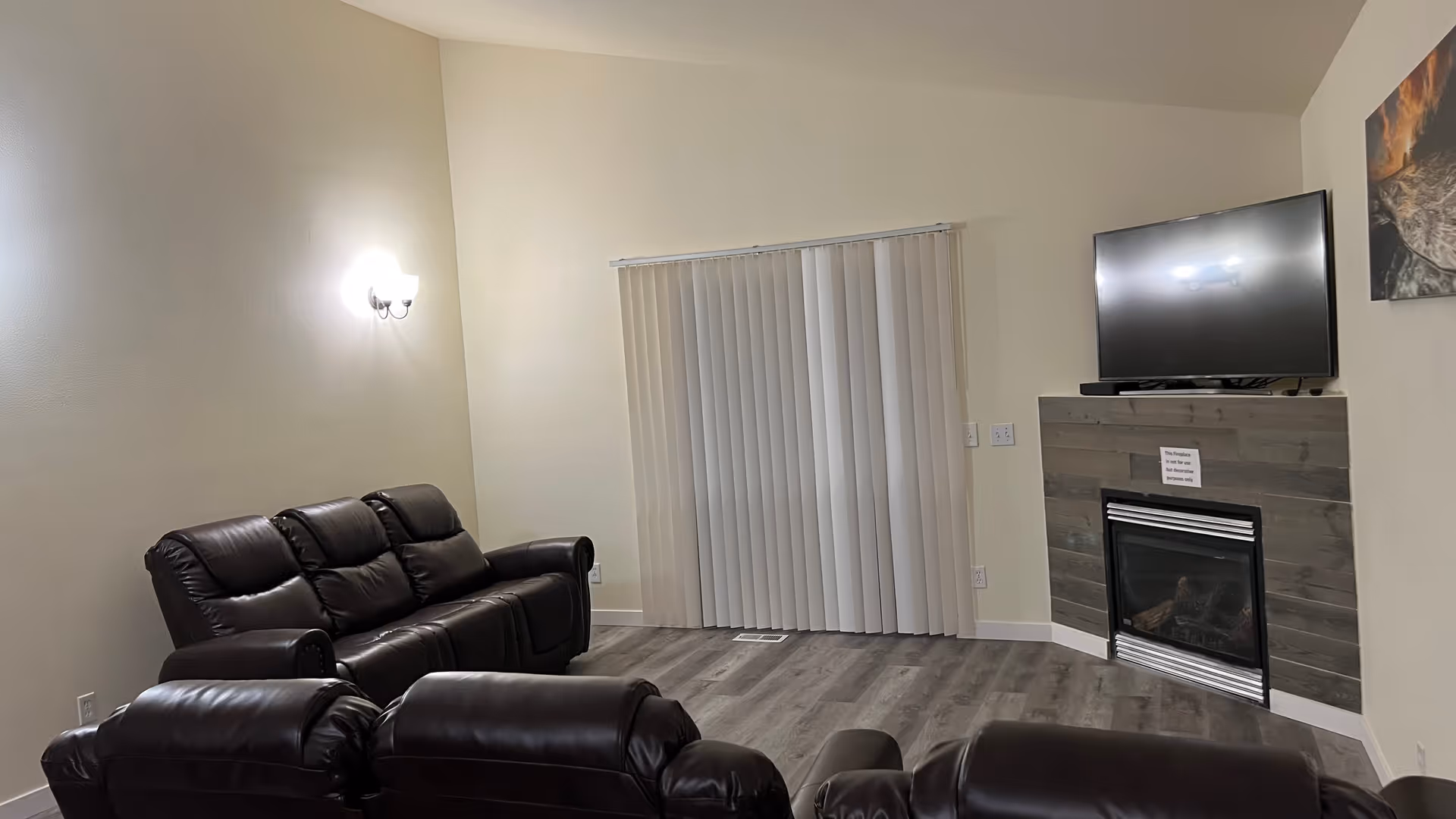 Cozy living room with brown leather seating, a stone fireplace, and a mounted TV.