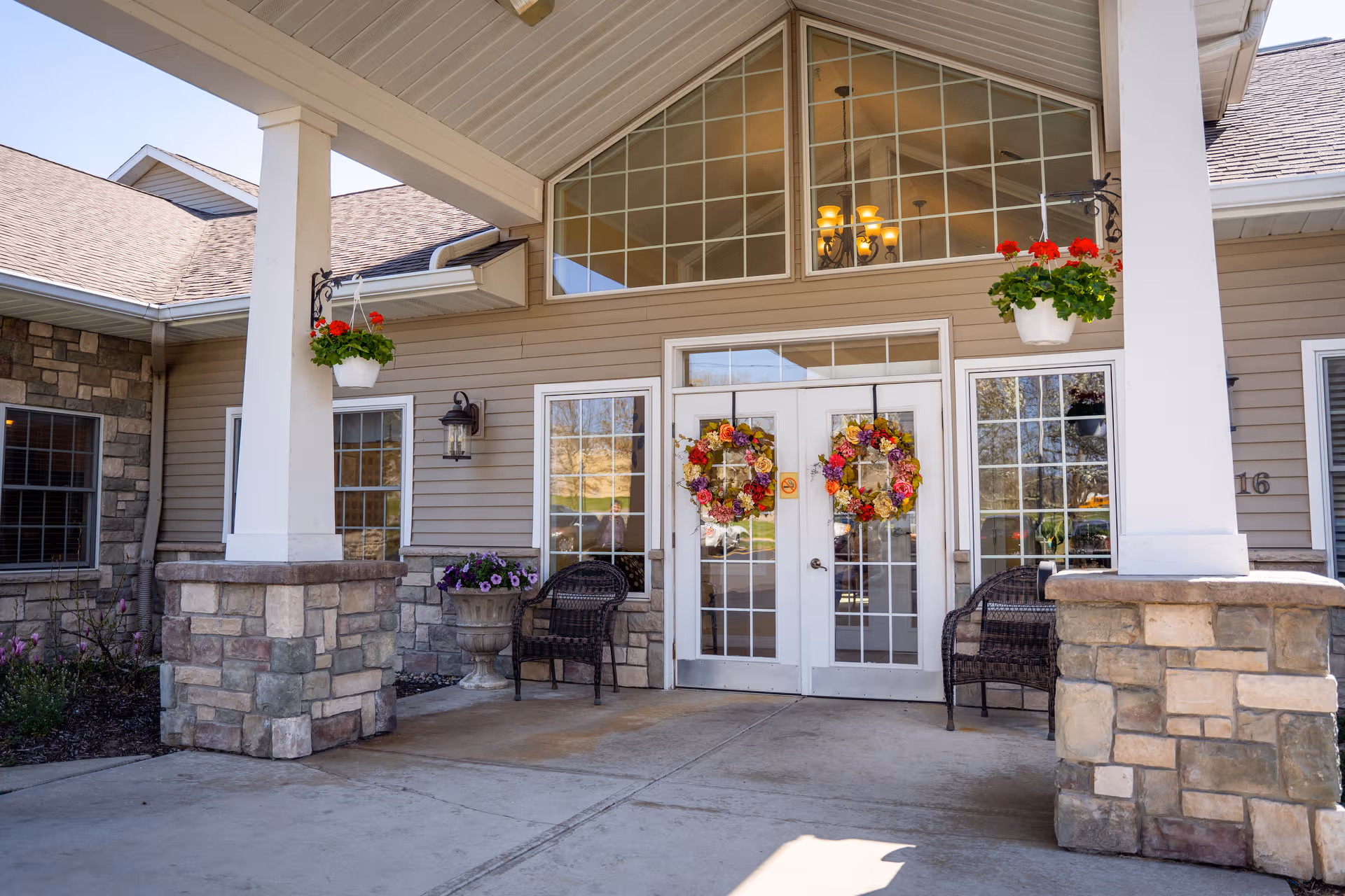 Front exterior of a memory care facility with double doors, wreaths, and benches.