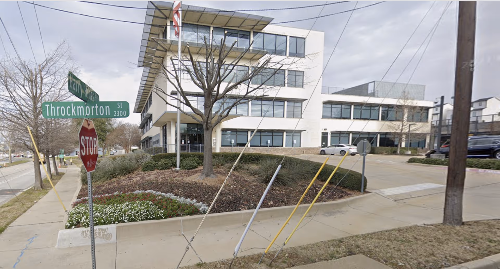 Modern multi-story senior living building at a street corner with sidewalks and street signs.