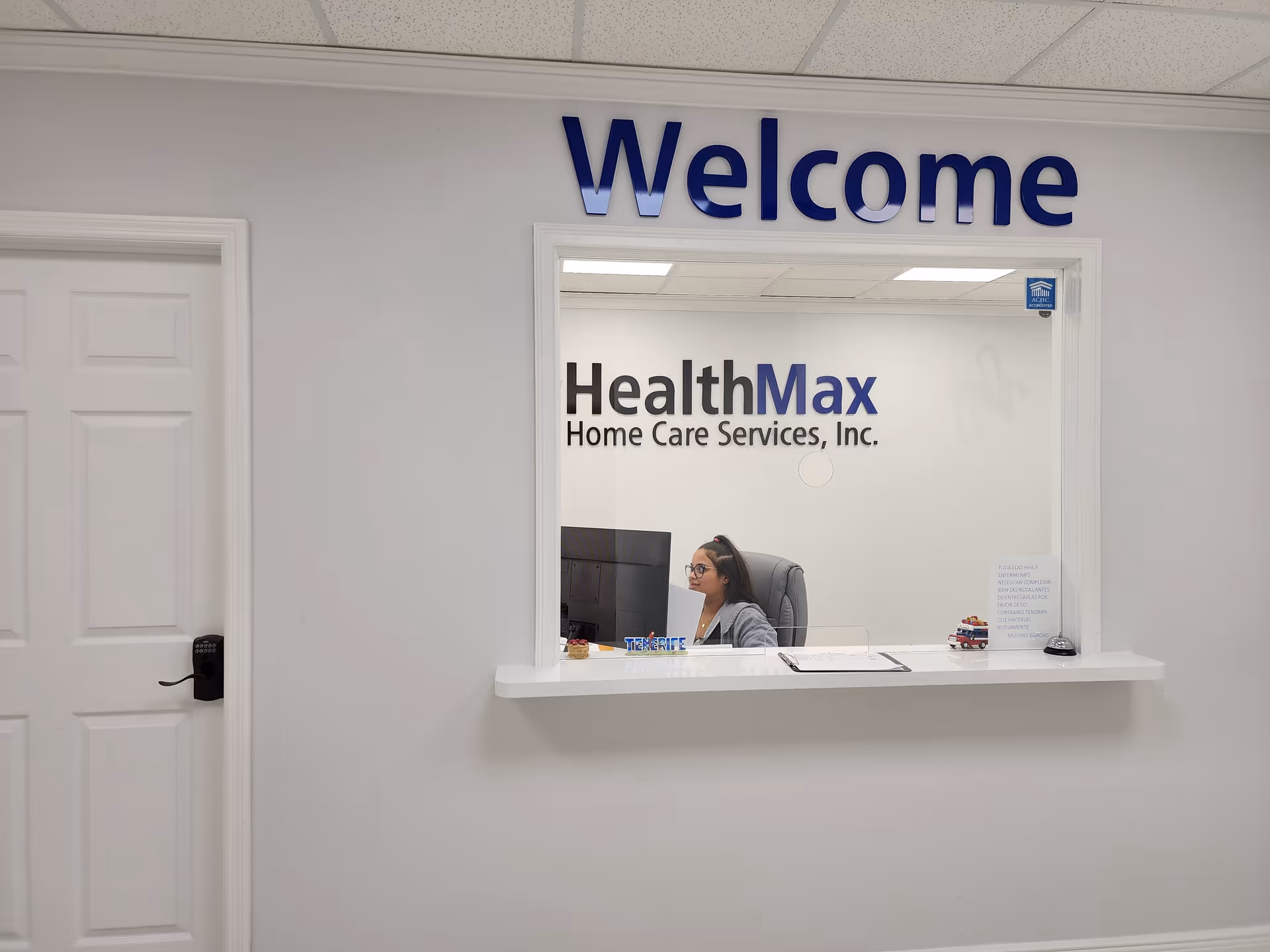 Reception area with HealthMax sign and a staff member at the window desk.