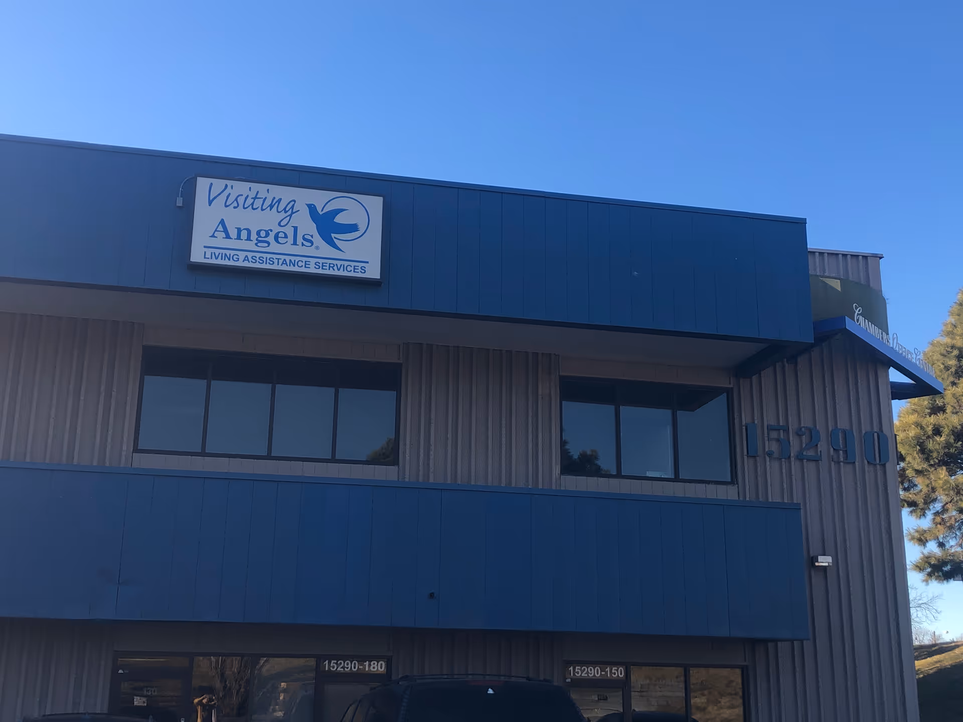 Exterior view of a blue-gray building with a Visiting Angels sign on the front.