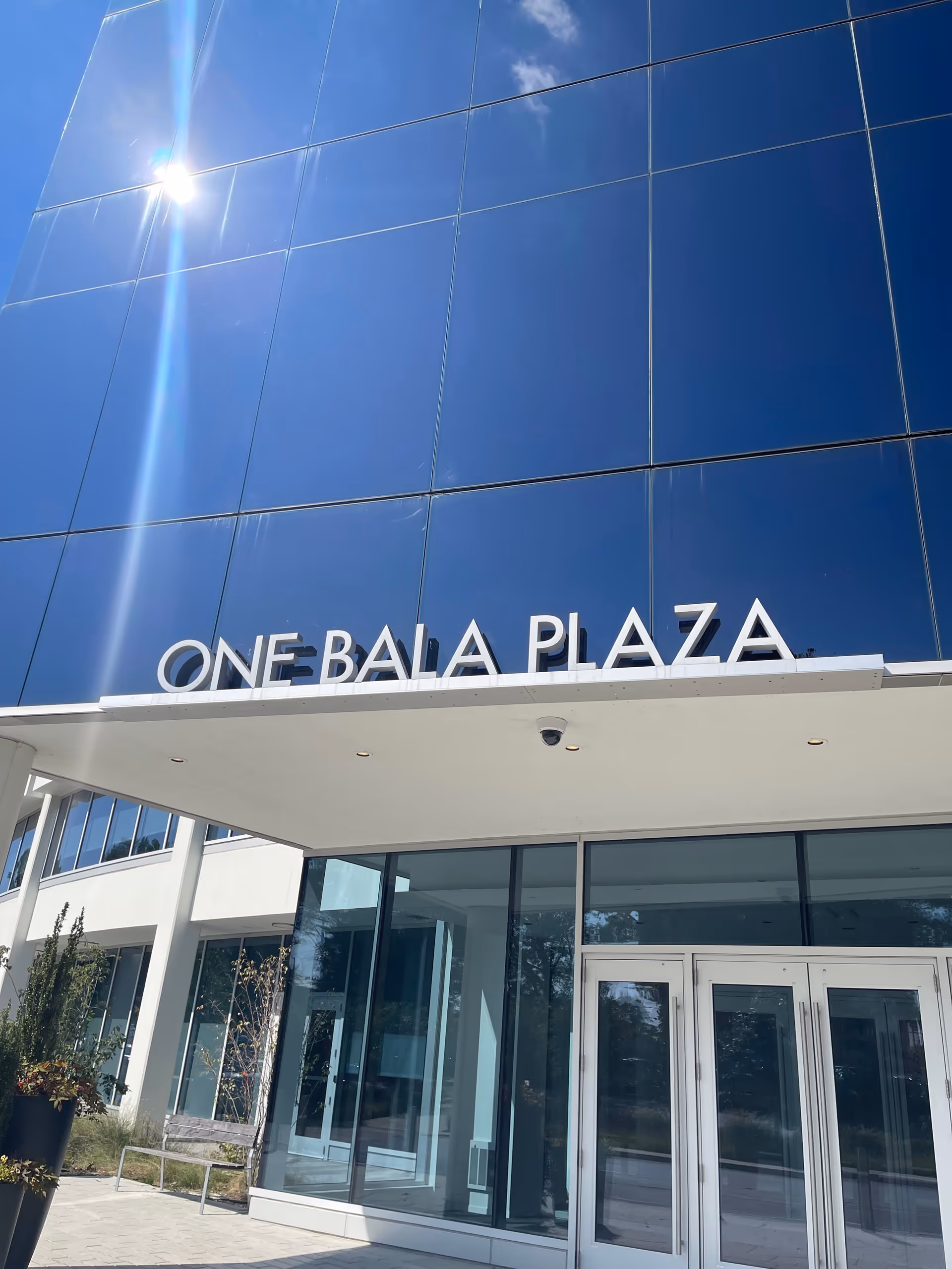Glass-front building facade with entrance and ONE BALA PLAZA signage.