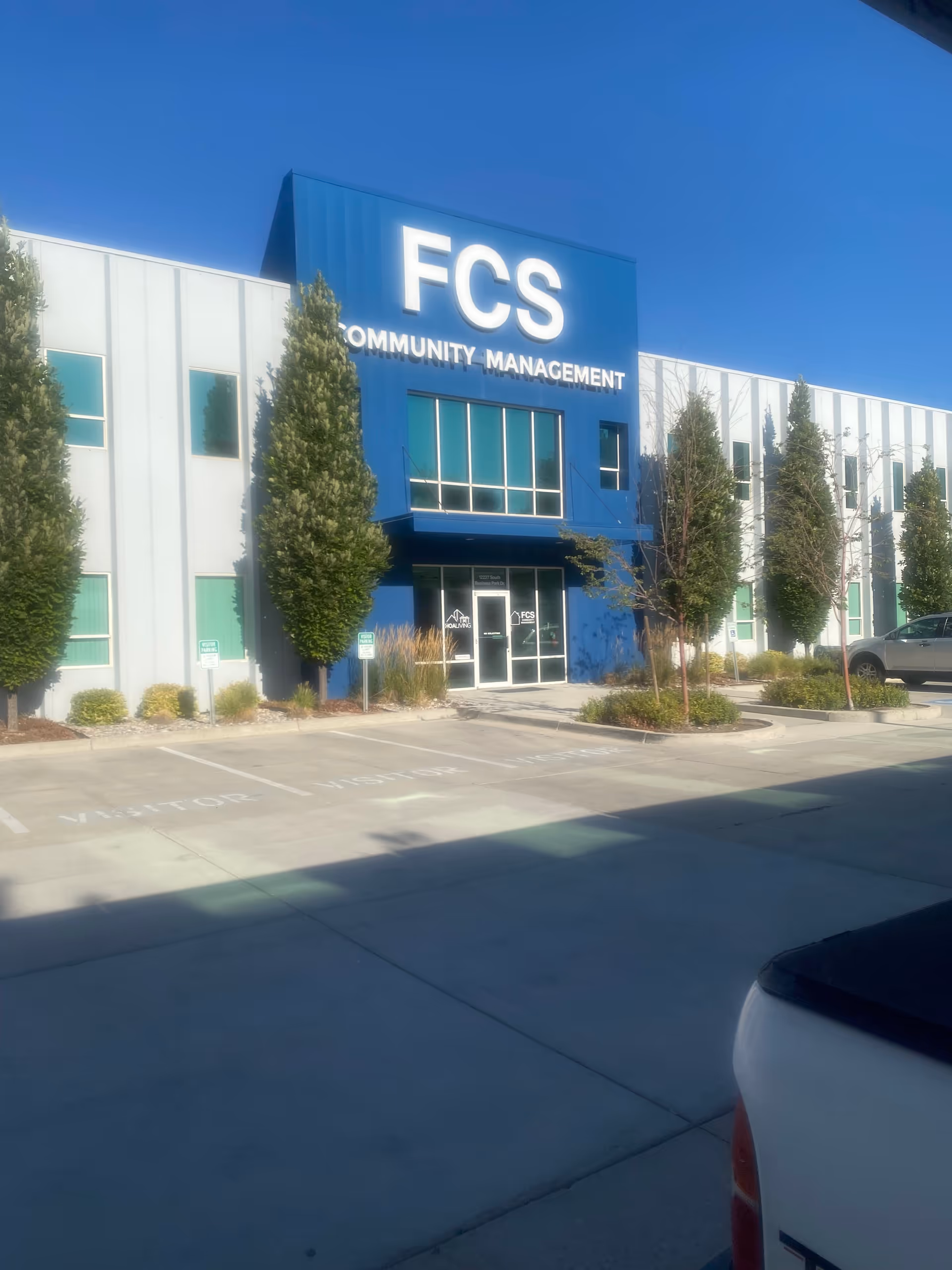 Exterior view of a modern blue-and-white building with FCS Community Management signage