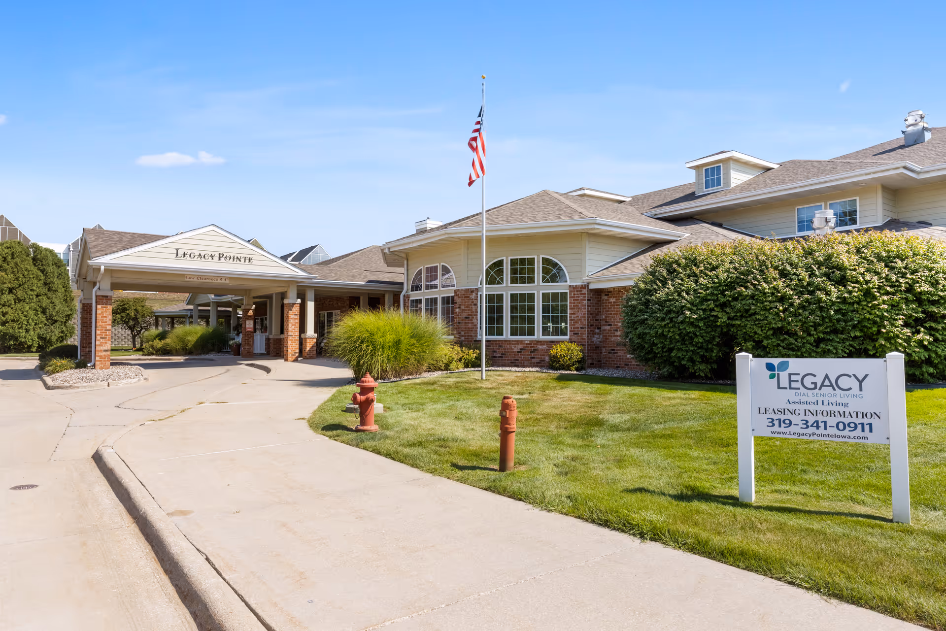 Exterior view of Legacy Senior Living building with entrance, sign, and manicured lawn.