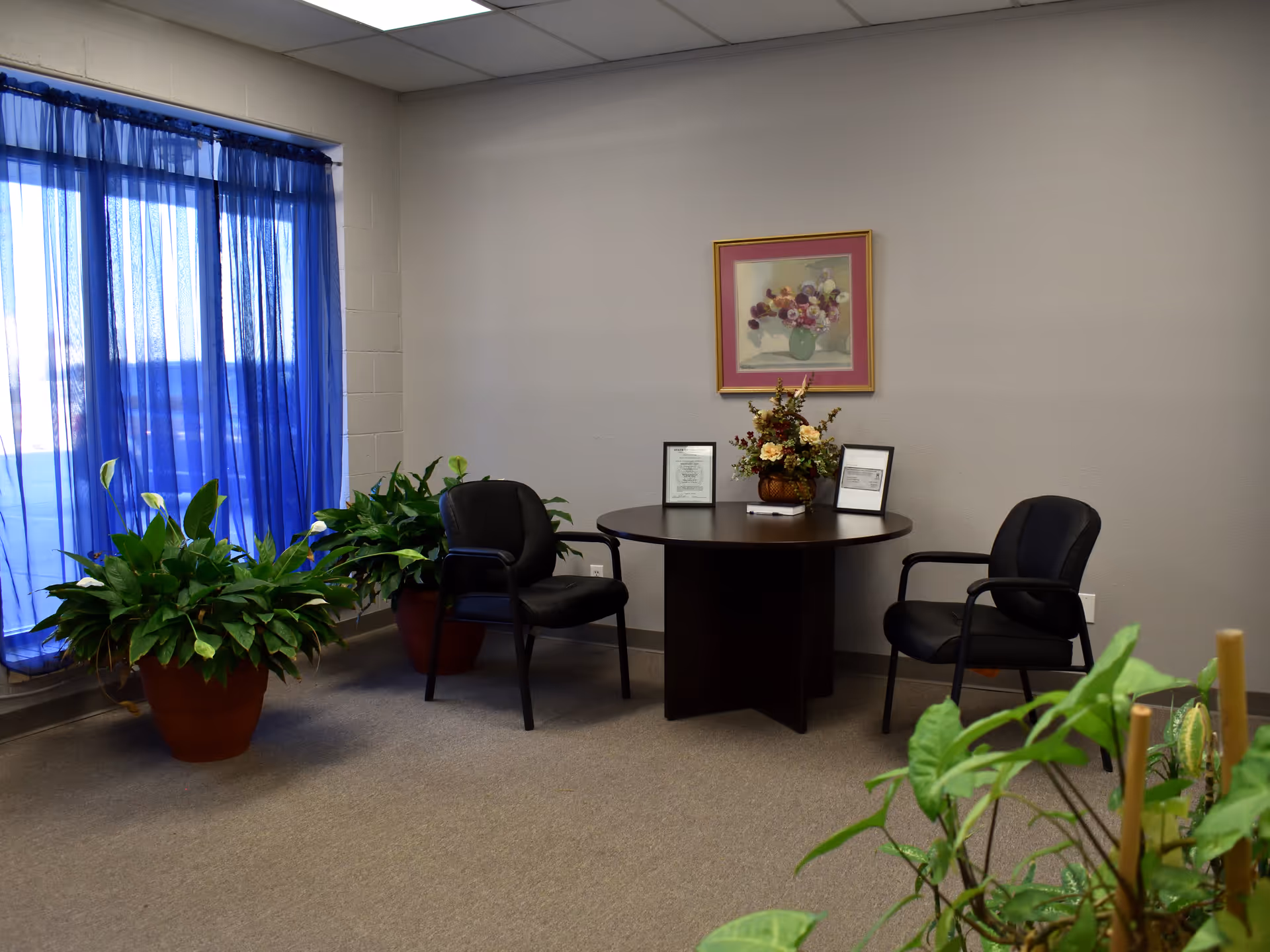 A small lobby area with a round table, chairs, and potted plants.