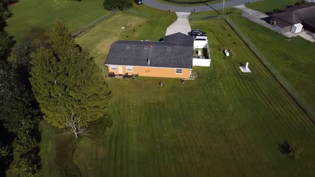 Aerial view of a single-story orange building with a large green lawn and driveway.
