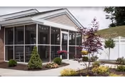 A single-story senior care facility with a screened front porch and large windows.