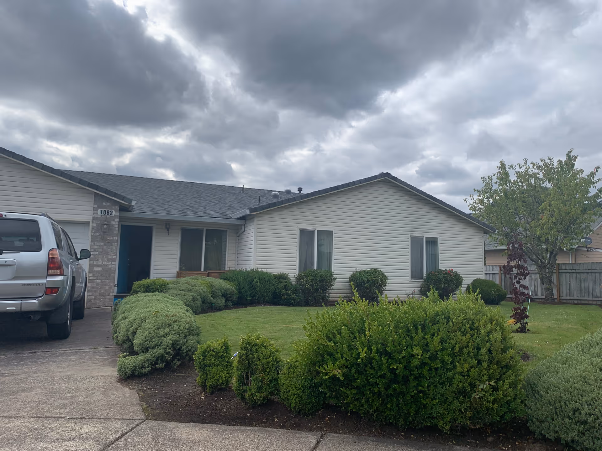 Front view of Evelyn's Adult Foster Home: single-story house with trimmed hedges and a parked SUV.