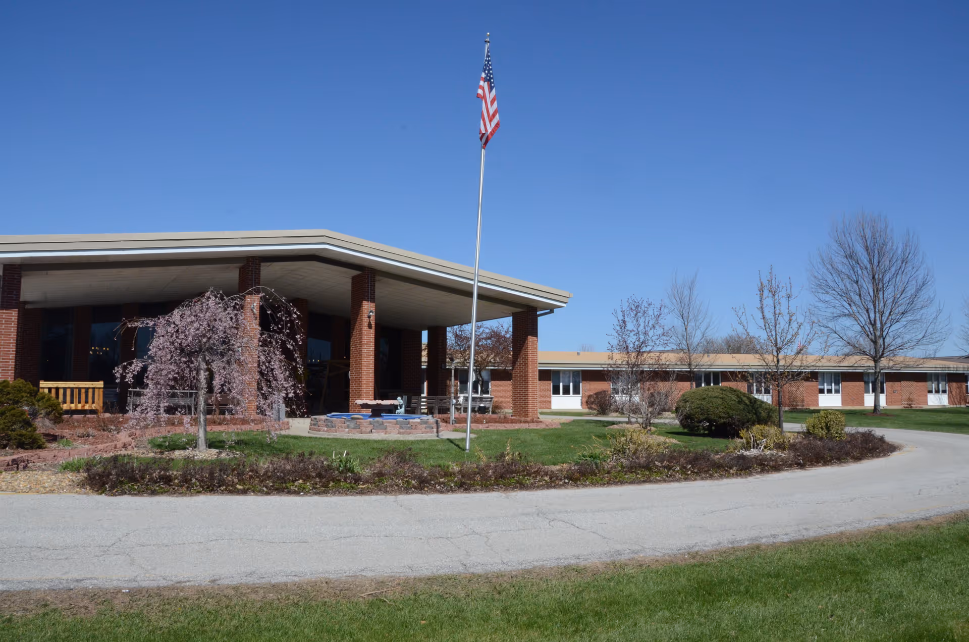 Exterior view of Amana Retirement Community Lakeview Village with flagpole and landscaped grounds.
