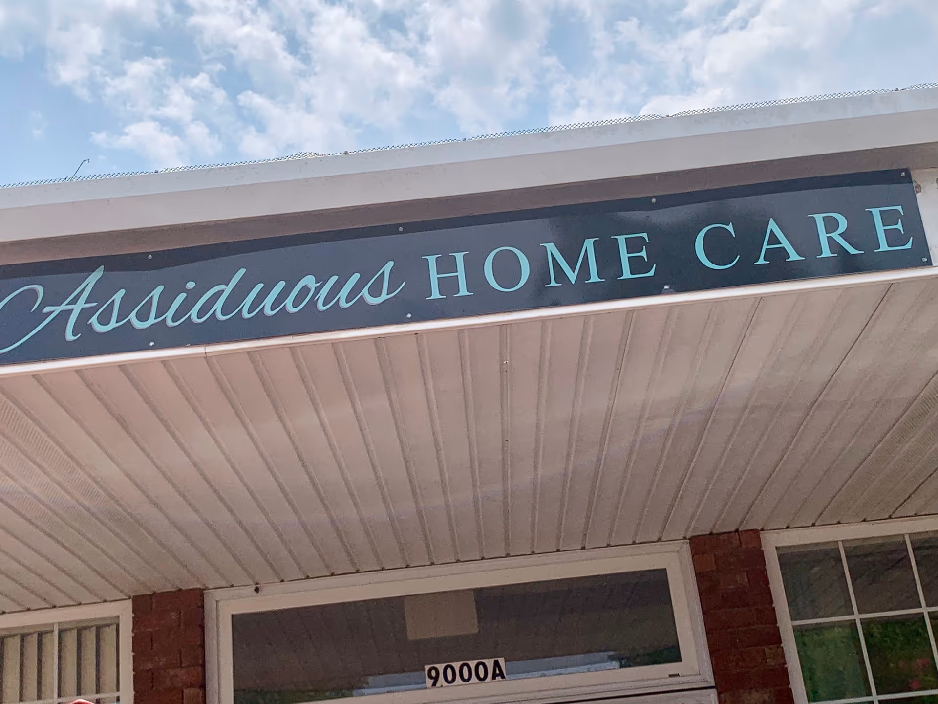 Close-up of the building front with a sign reading Assiduous Home Care.