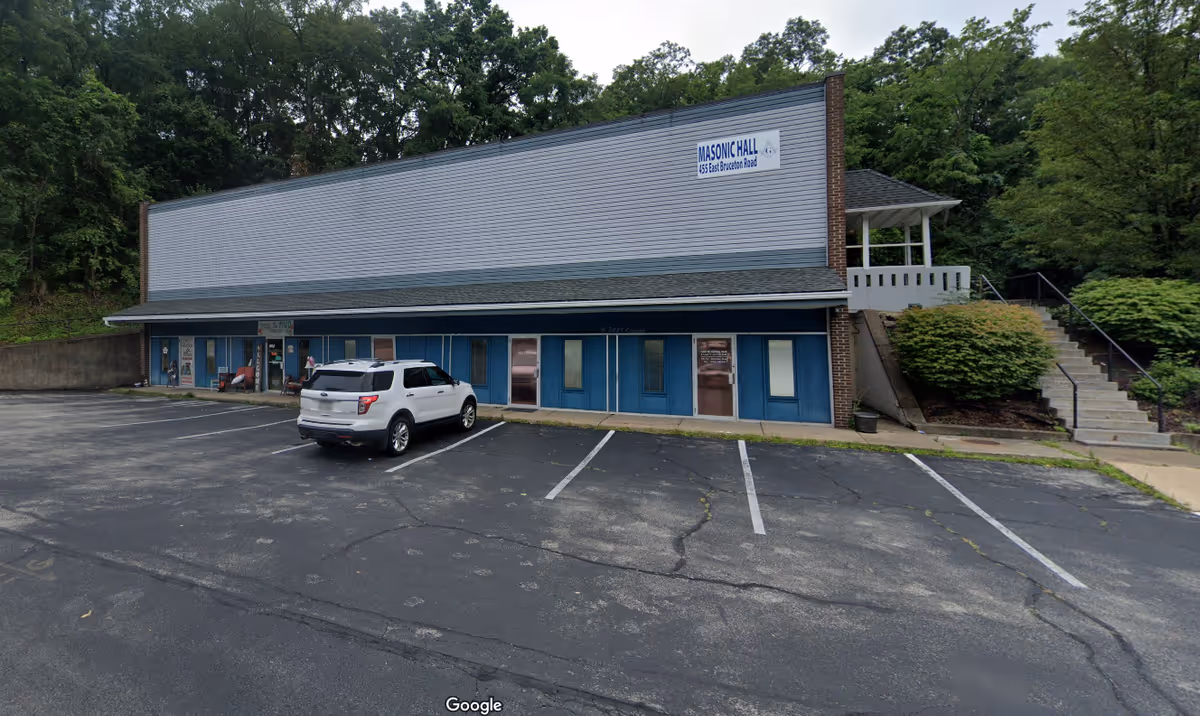 Front view of a single-story building with blue doors and a parking lot.