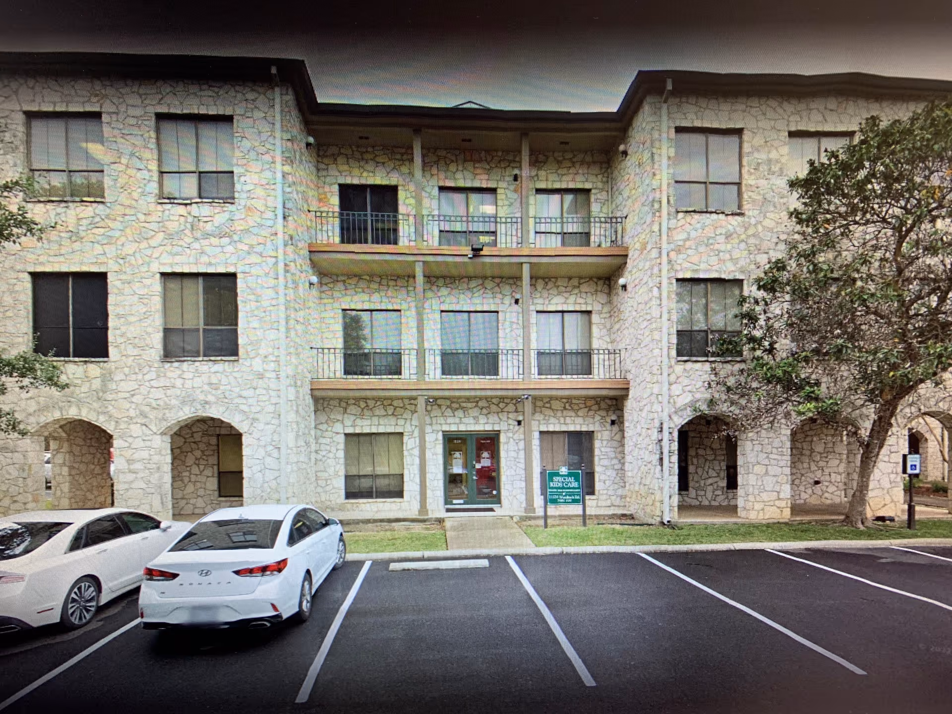 Exterior stone building labeled Special Kids Care with balconies and a front parking lot.