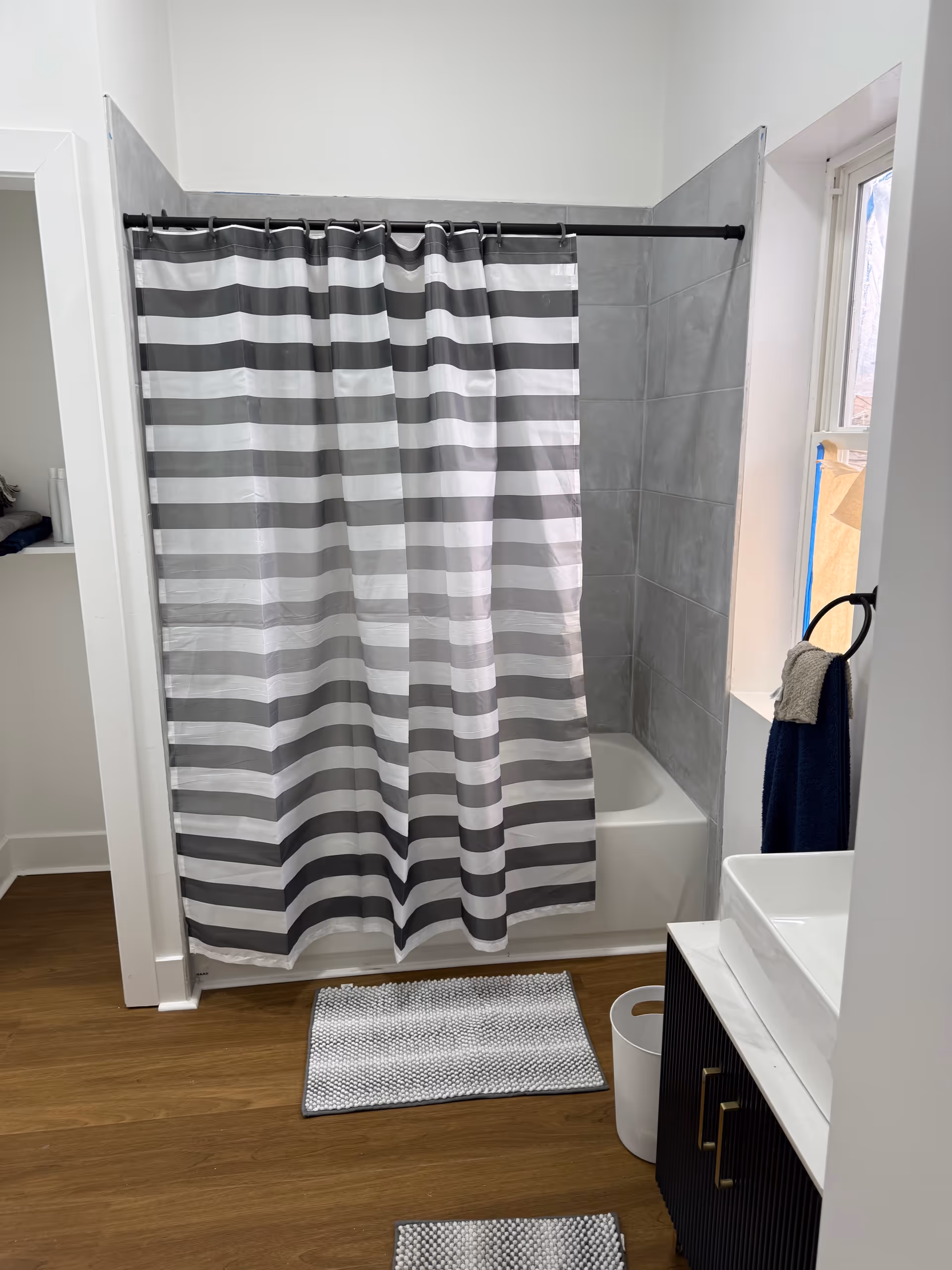 A striped shower curtain covers a bathtub in a modern bathroom.