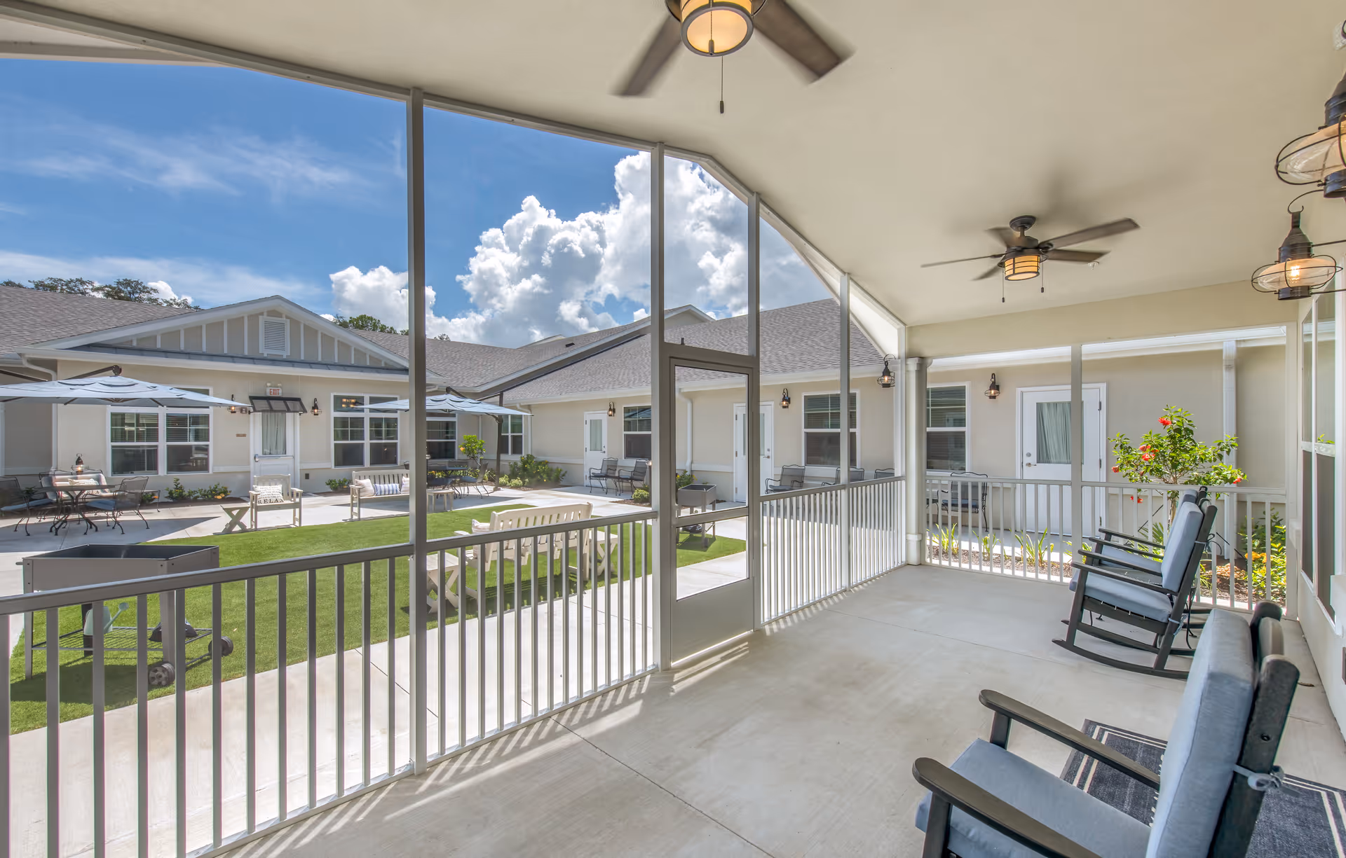 Screened patio overlooking a central courtyard with outdoor seating and unit entrances.