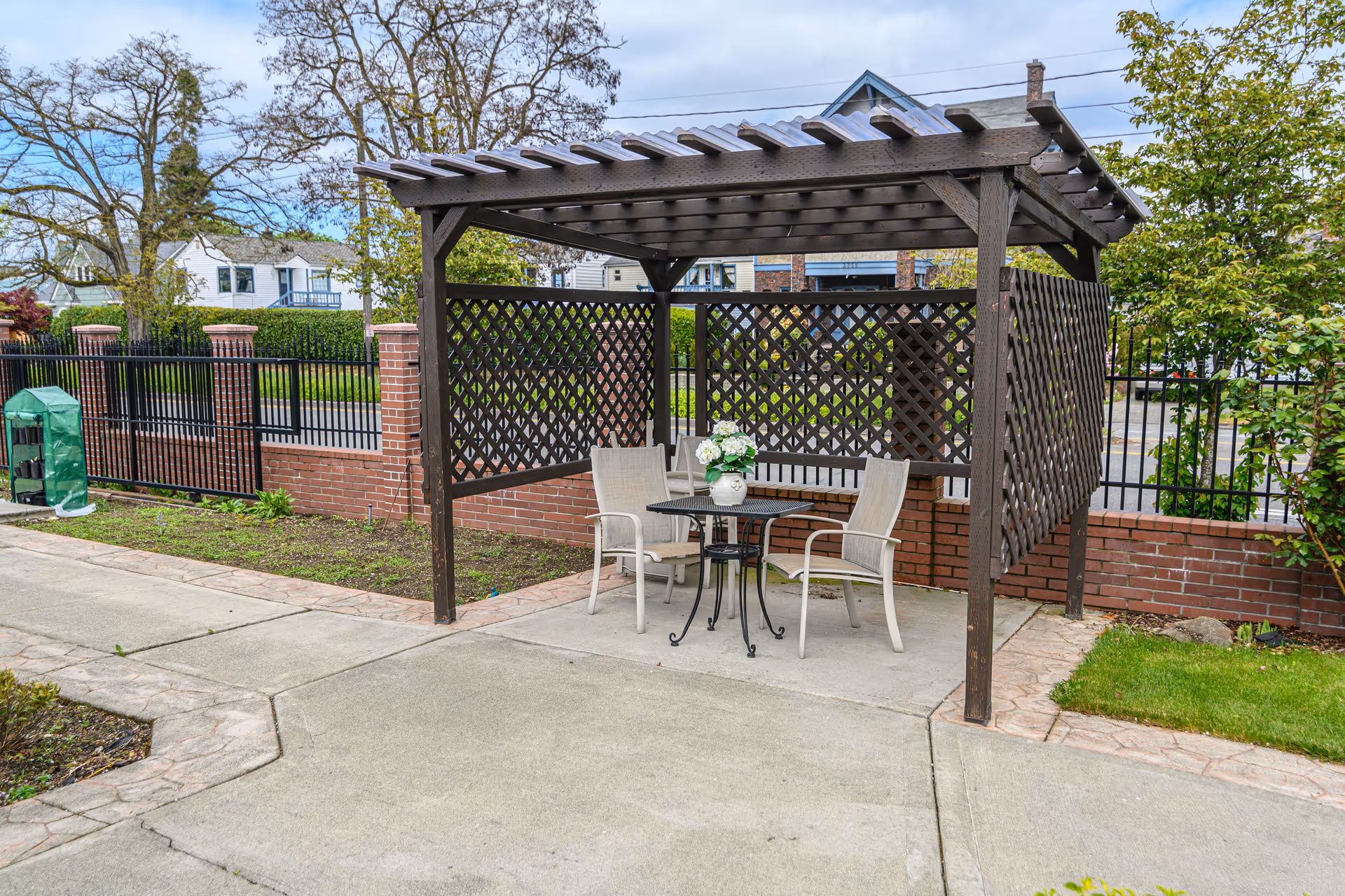 Outdoor brick patio with lattice pergola, table, four chairs, and flower centerpiece.