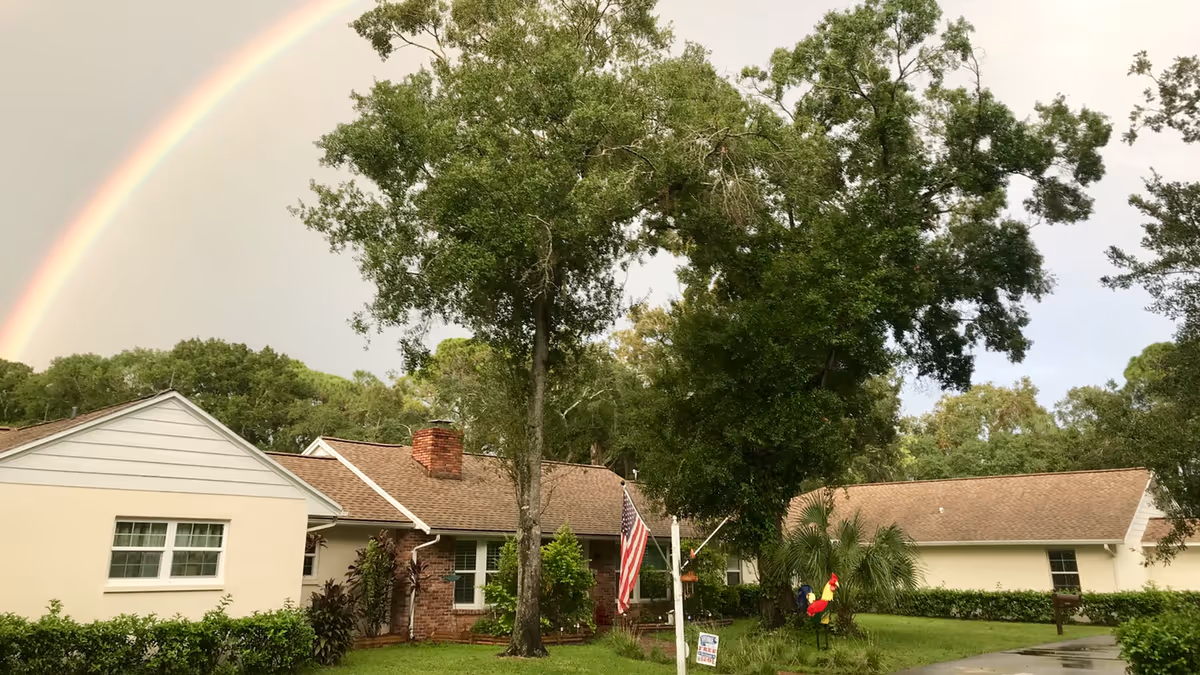 Exterior of a one-story assisted living facility with a rainbow above the front yard.