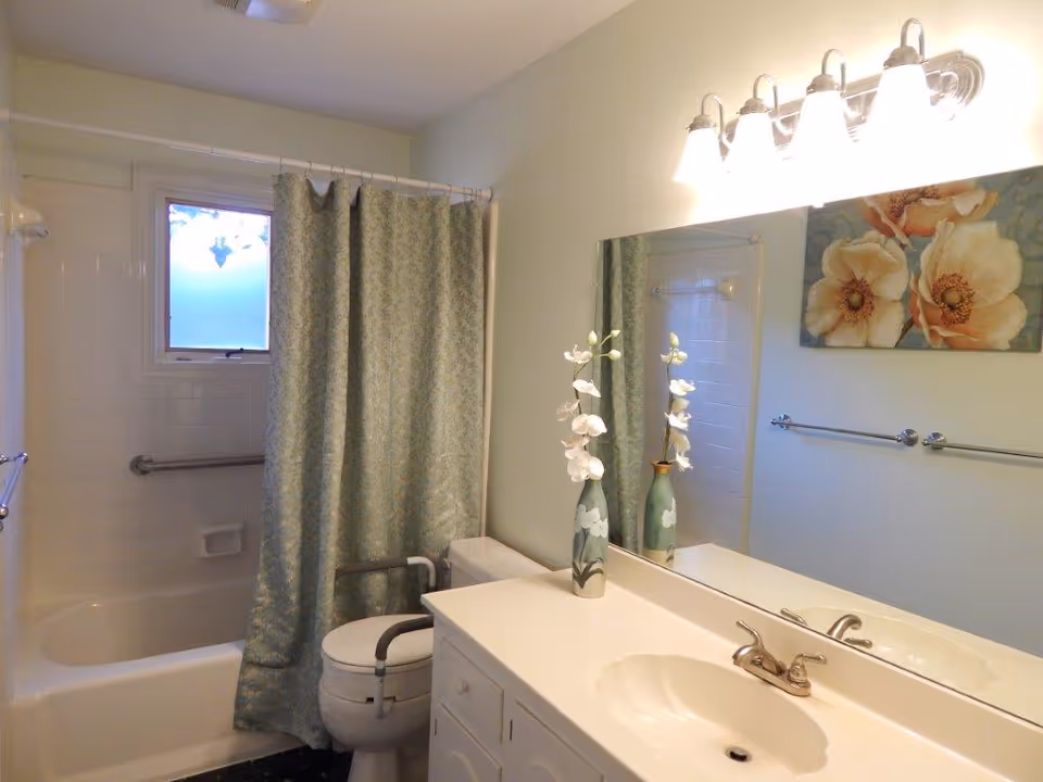 Bathroom at Bright Horizon Senior Care with sink, mirror, shower curtain, and blue decor.