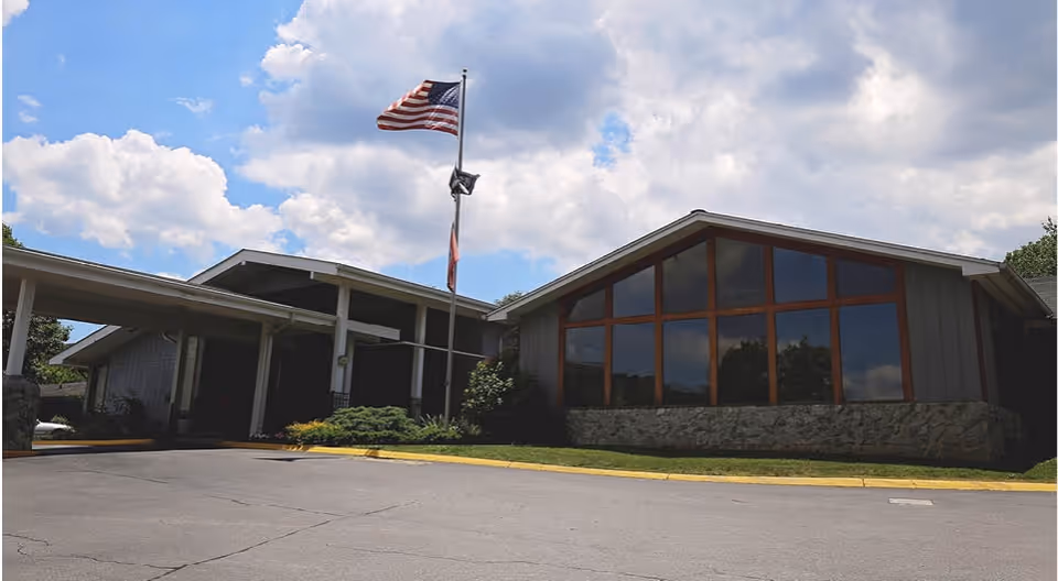 Exterior view of Holston Rehabilitation and Care Center with flagpole and large glass windows.