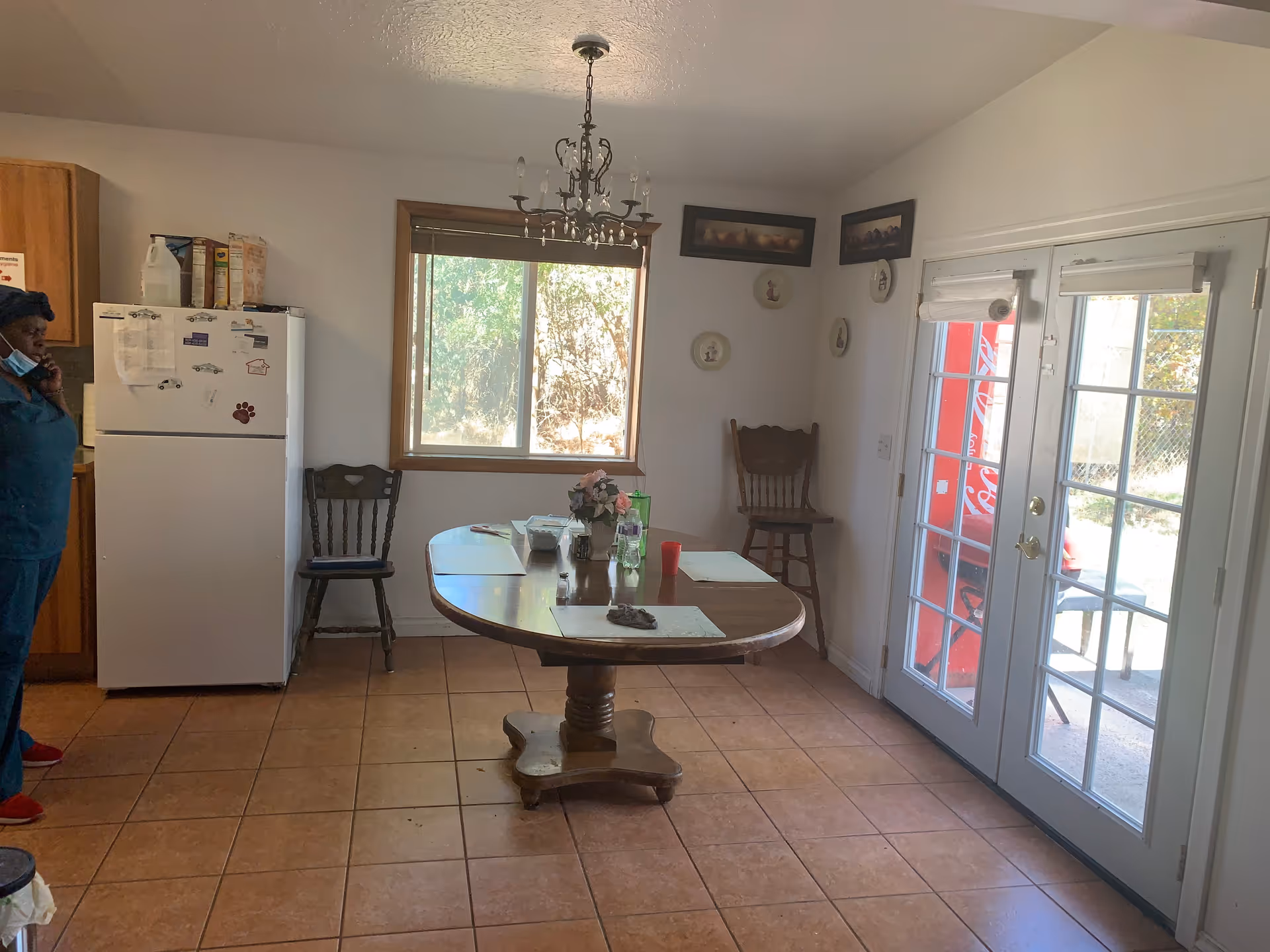 Senior living dining room with wooden table, chandelier, window, and French doors.