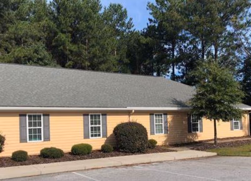 Sunrise at Parkway exterior: a peach-colored single-story building with windows and shrubs