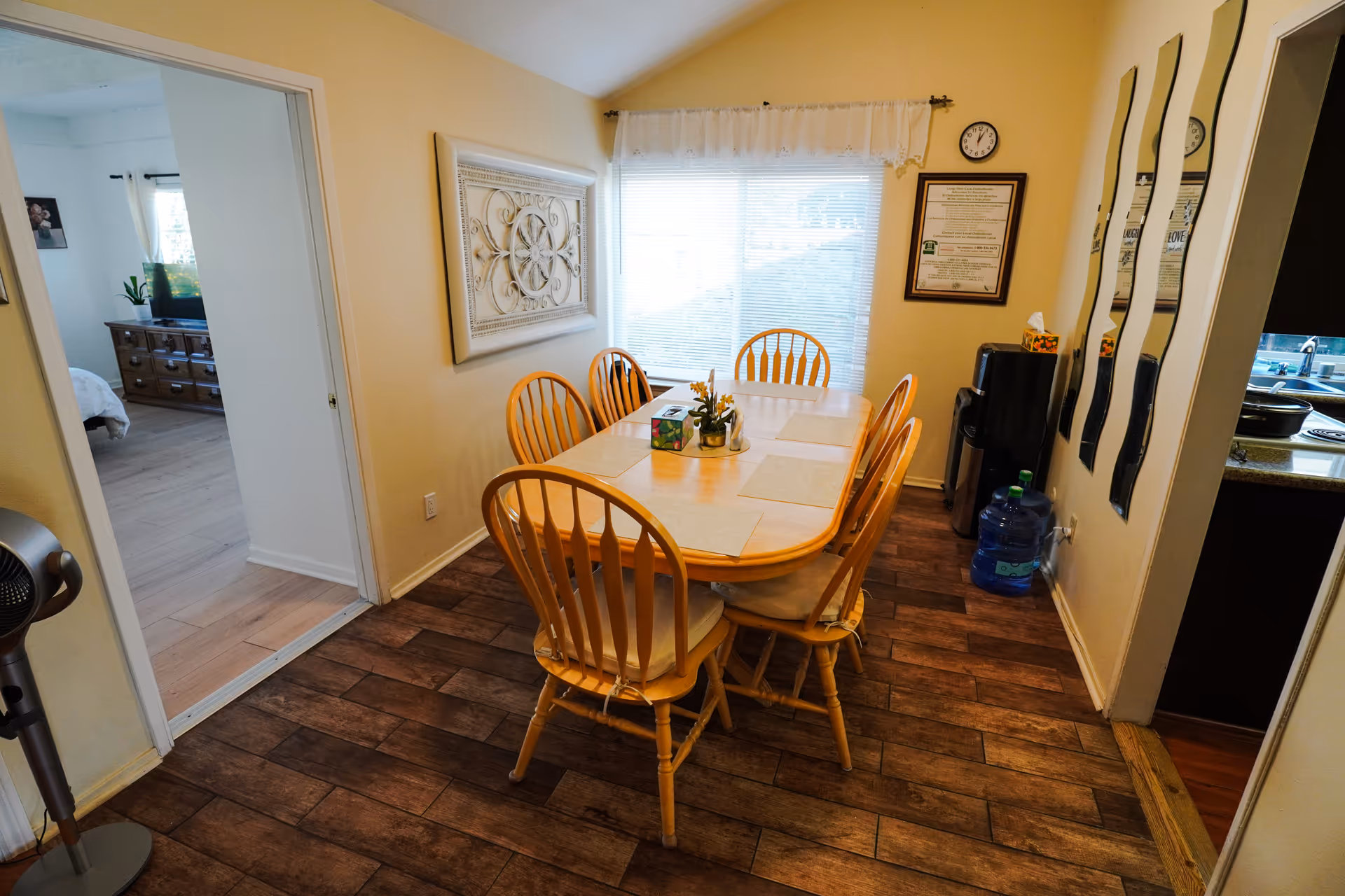 A dining room with a wooden table and multiple chairs near a window.