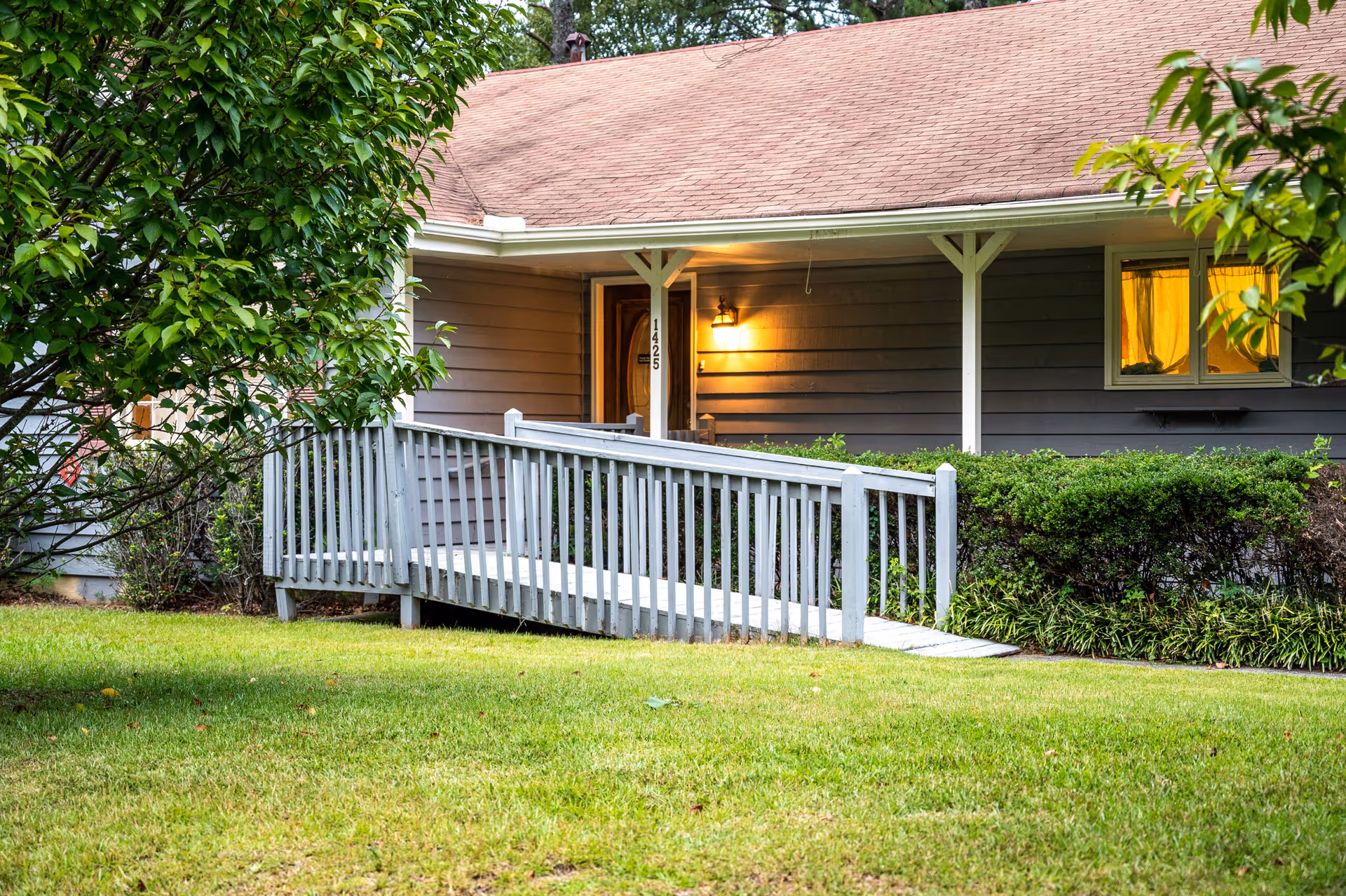 Front entrance of a single-story home with a wooden ramp and porch railing.