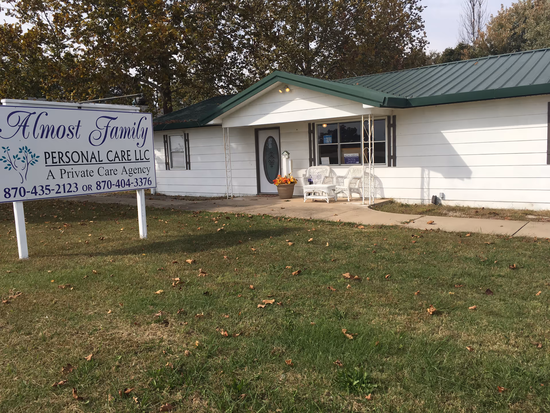 Front view of a single-story care facility with a sign and white outdoor seating.