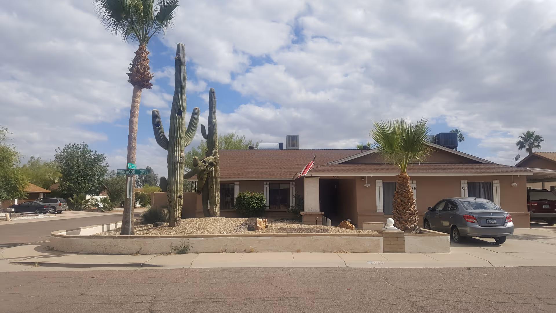 Front view of a single-story care home with desert landscaping and a parked car.