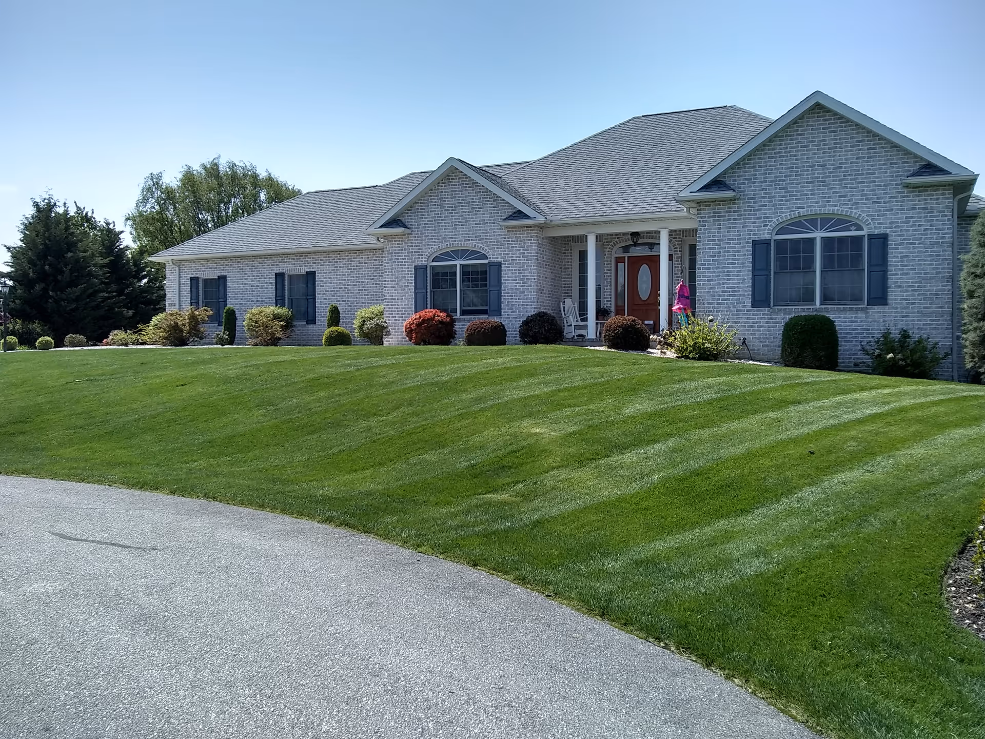 Front exterior view of a brick senior living facility with a manicured lawn.