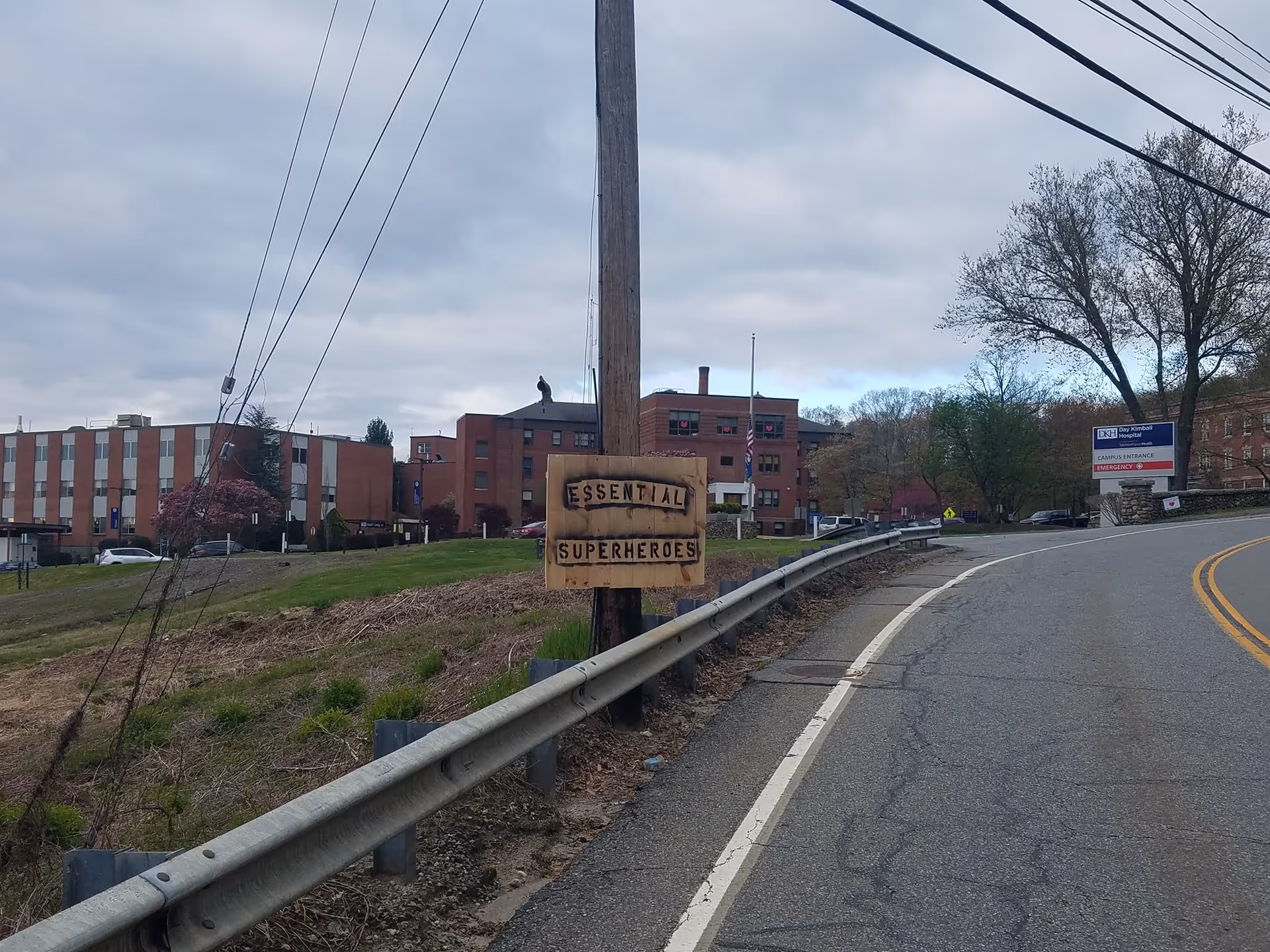 Exterior view of brick campus buildings along a curved road with a wooden sign.