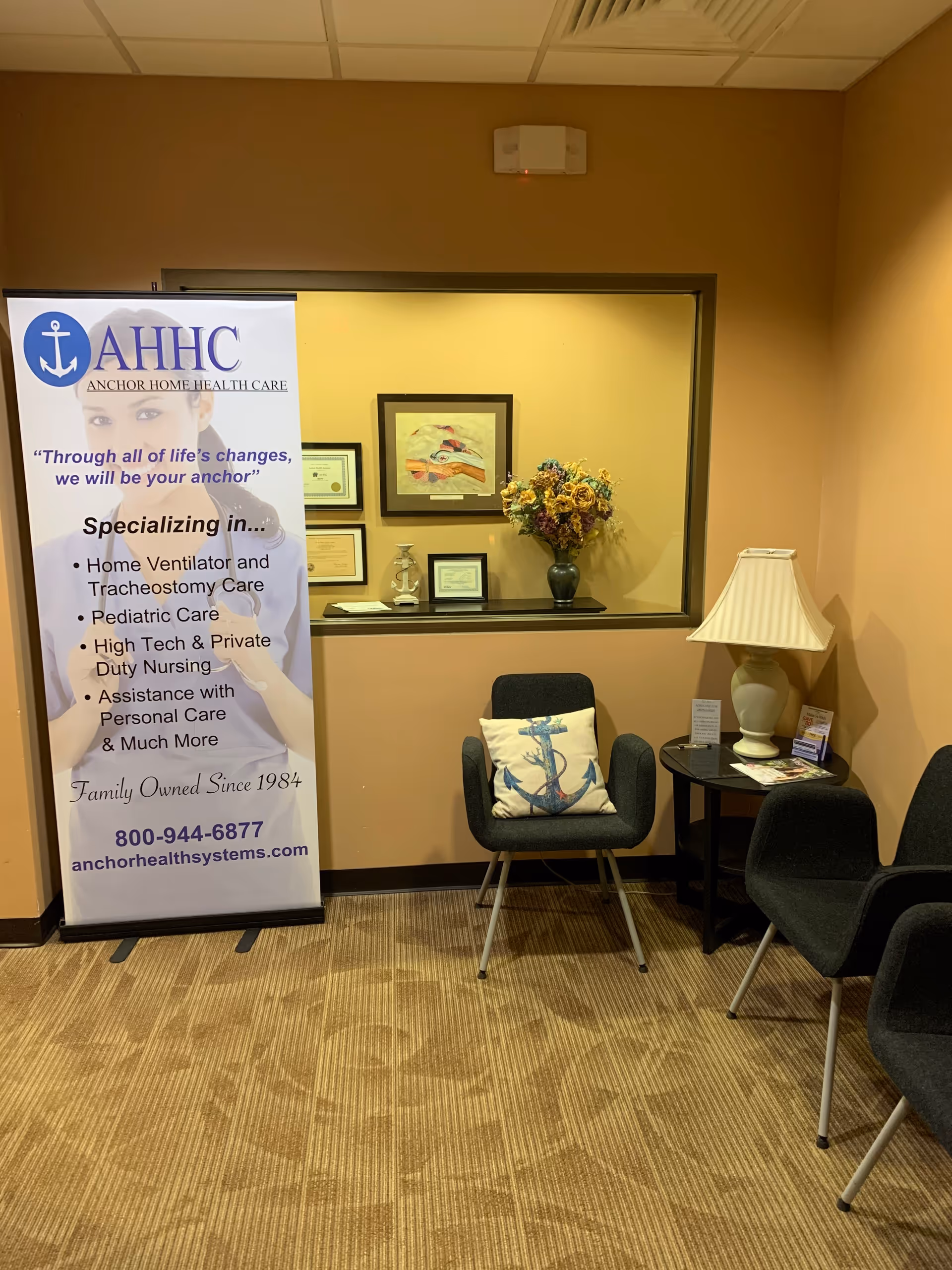 Waiting area in a facility lobby with an Anchor Home Health Care banner and chairs.