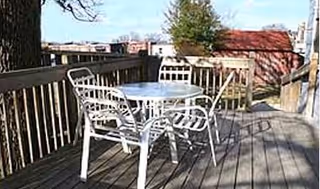 Outdoor wooden deck with a white metal table and chairs at Evergreen Valley.