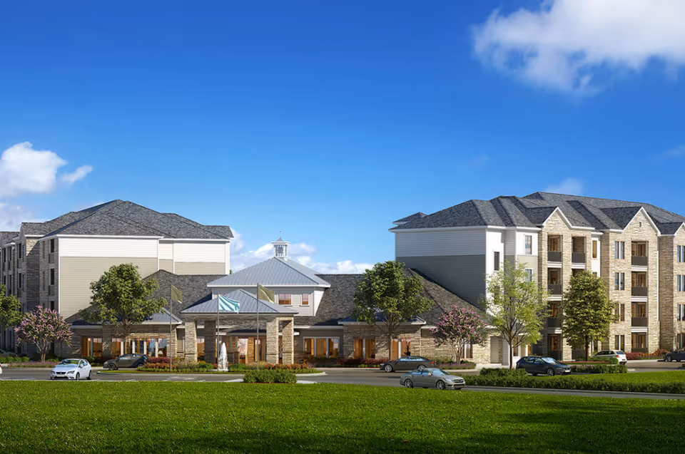 Exterior view of a multi-building senior living campus with lawn and parked cars