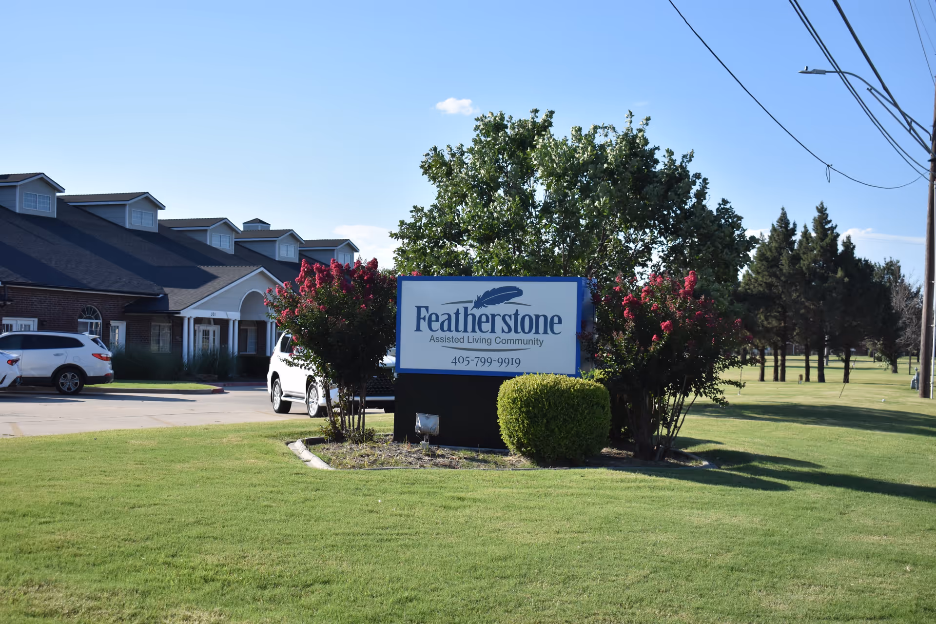 Featherstone Assisted Living Community sign beside a building with manicured lawn outdoors.