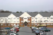Sunnybrook Senior building exterior with a central entrance and parked cars in the lot.