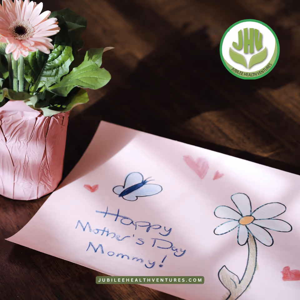 Pink vase with flowers and a Mother's Day card on a wooden table