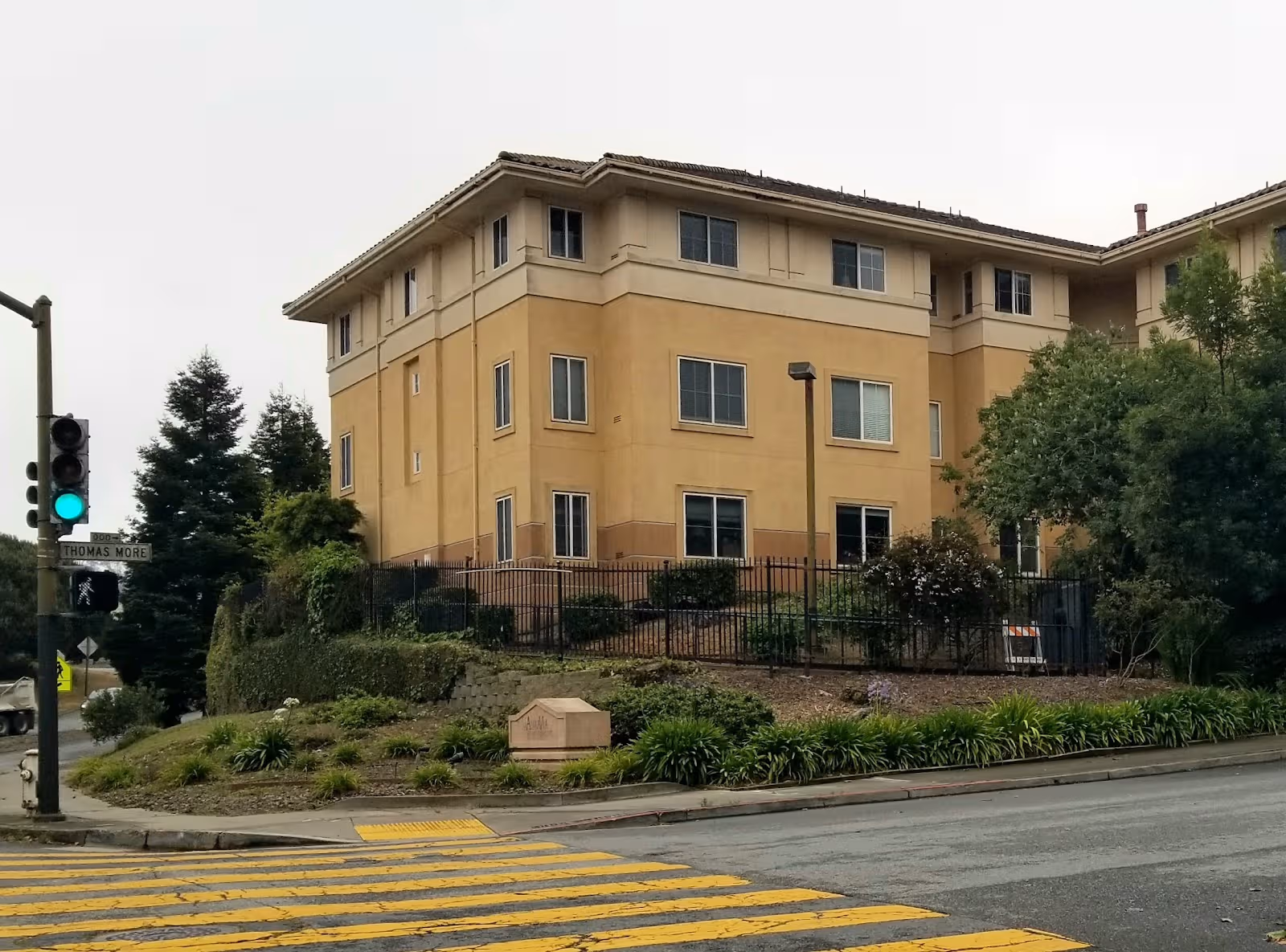 Exterior view of AlmaVia of San Francisco, a tan multi-story senior living building with landscaping.