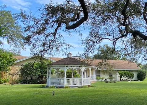 Exterior view of Lincolnshire Assisted Living with a white gazebo on a green lawn.