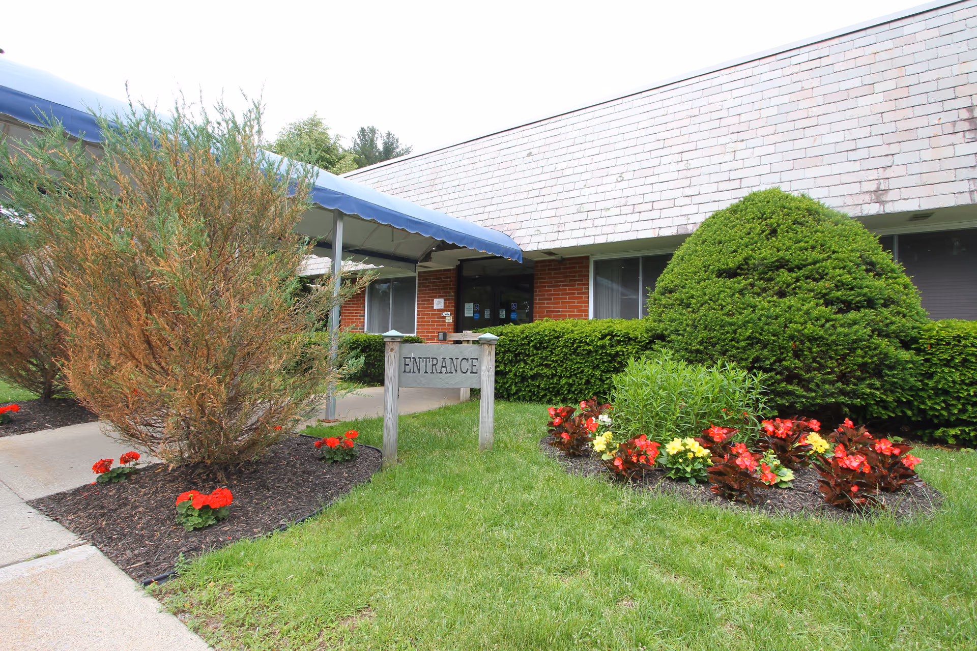Exterior view of Granville Center for Rehabilitation and Nursing entrance with a blue canopy and flowers