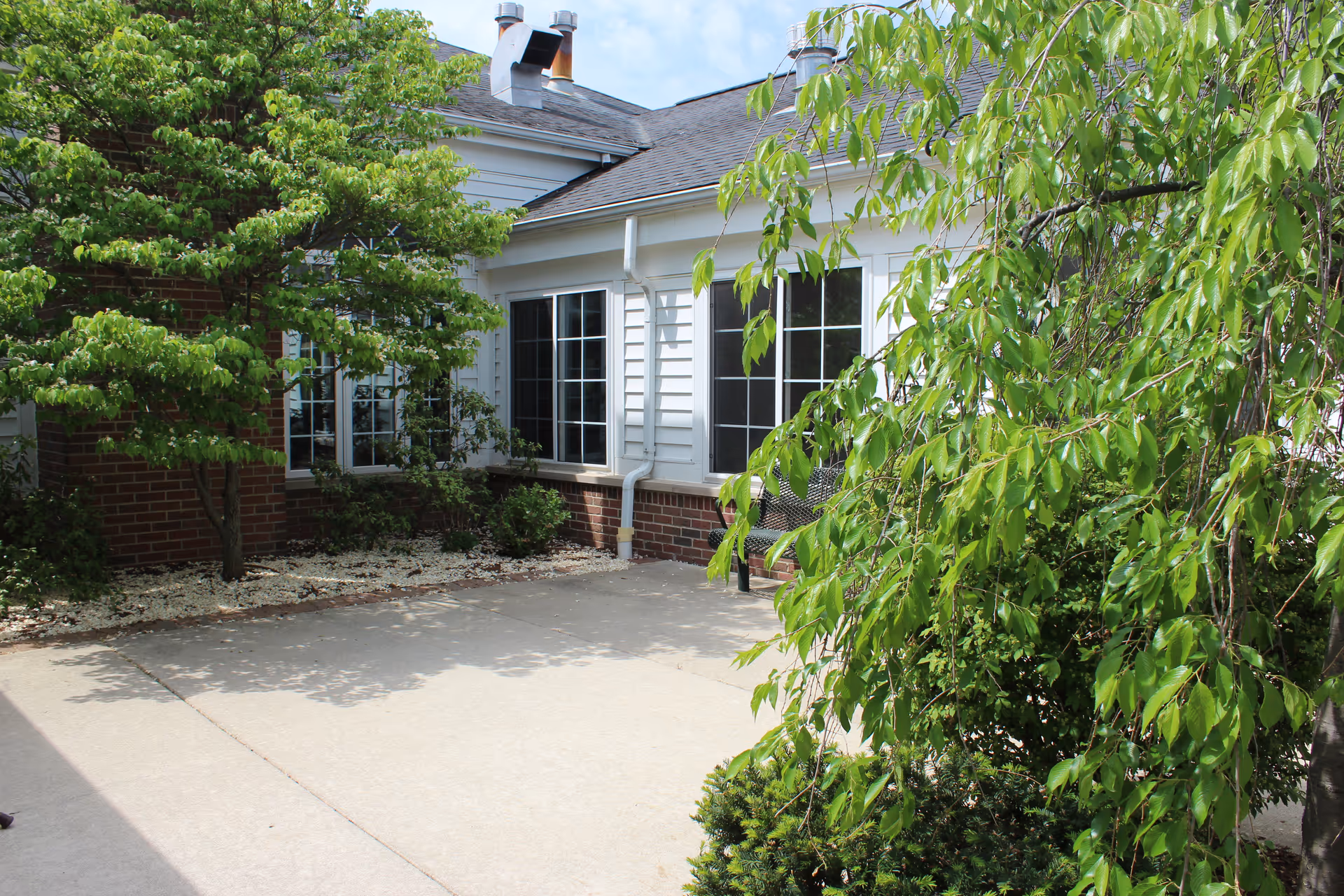 Exterior view of Crystal Creek Assisted Living and Memory Care with greenery and a paved area.