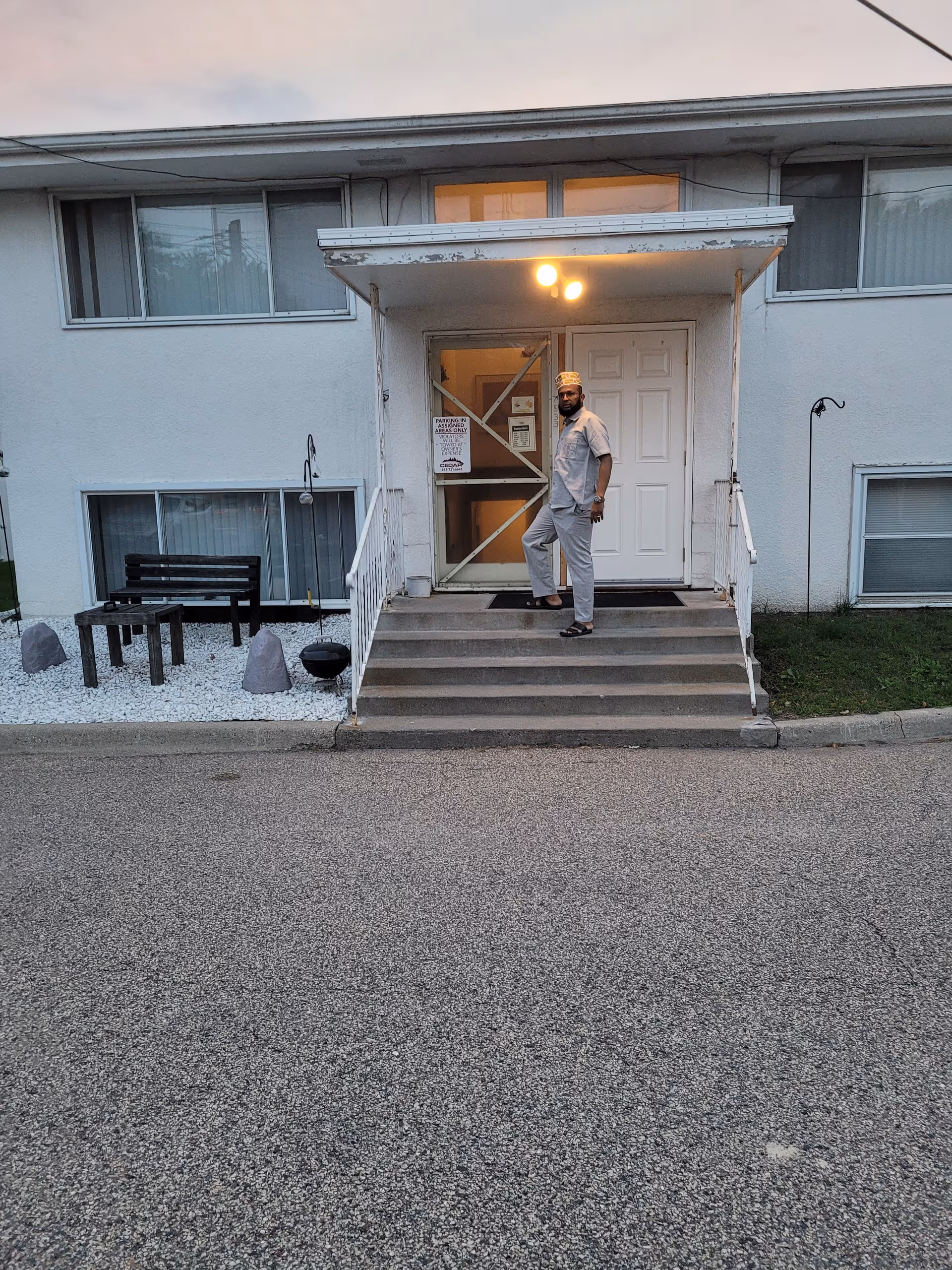 Man in scrubs stands on steps at the entrance of a senior care facility.