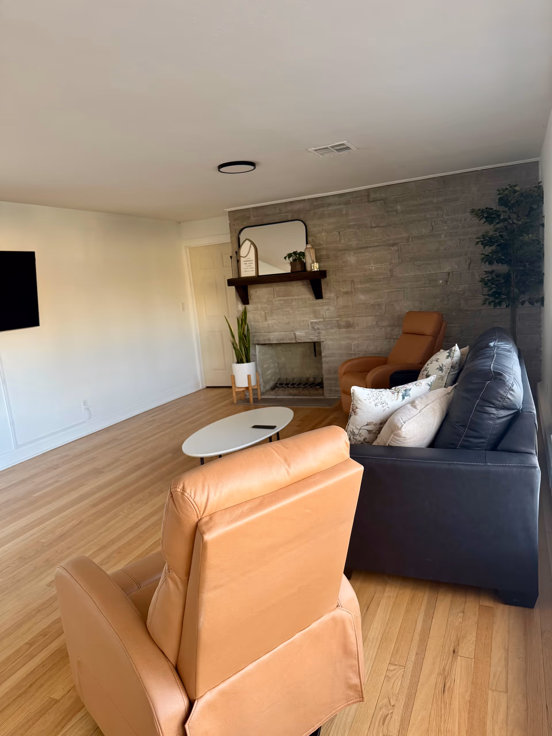 Cozy senior living lounge with seating, fireplace, TV, and decorative plants.
