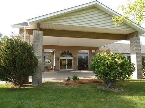 Front entrance of Highland Park Assisted Living with a covered driveway and landscaping