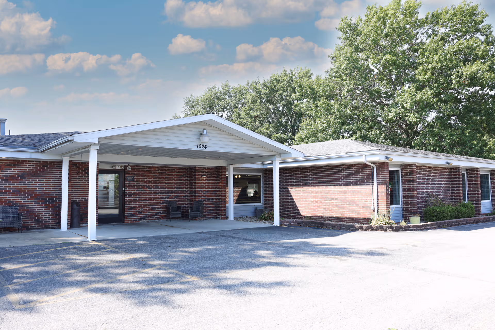 Exterior view of a brick senior living facility with a covered entrance.