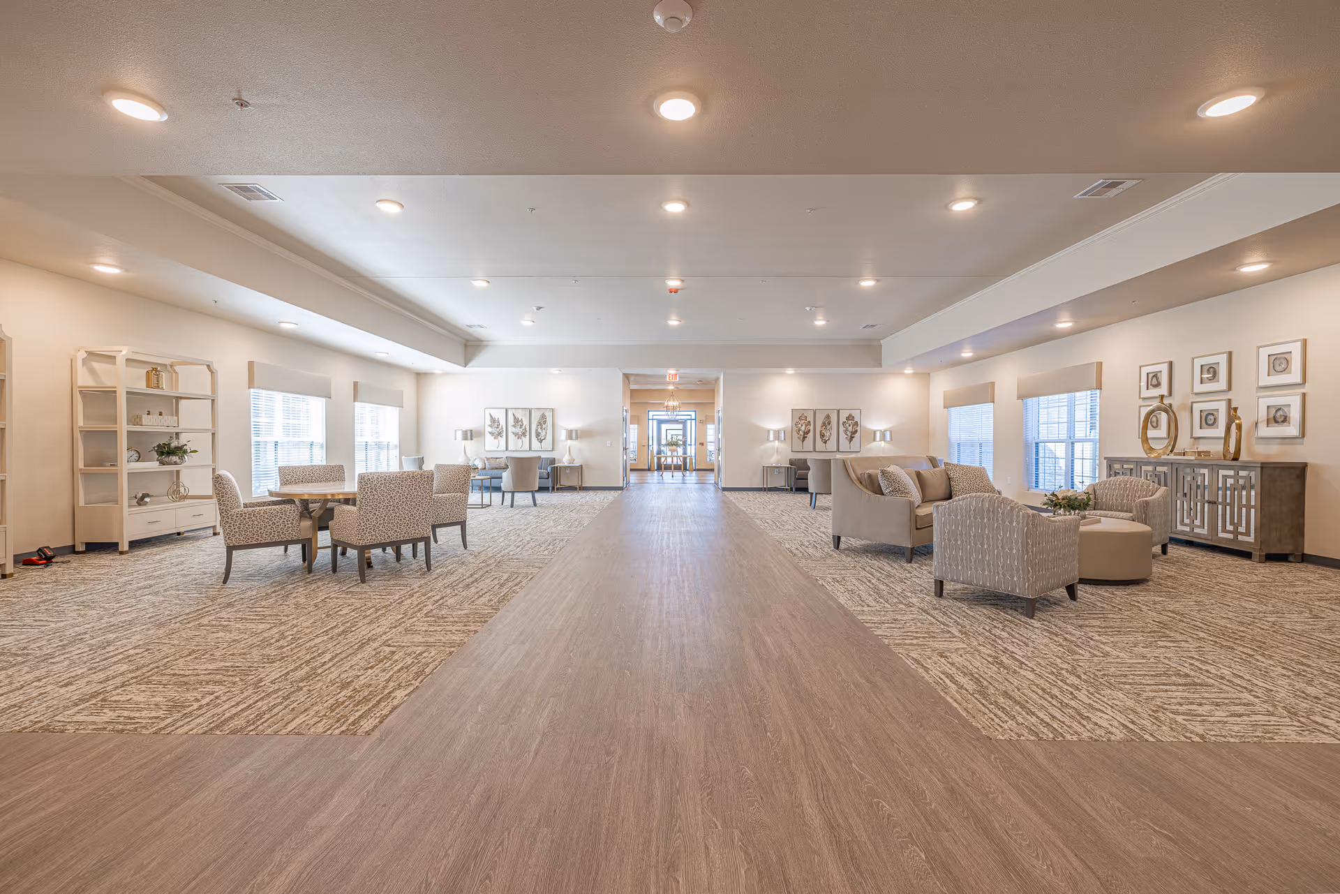 A spacious senior living lobby with seating areas, art, and a central walkway.