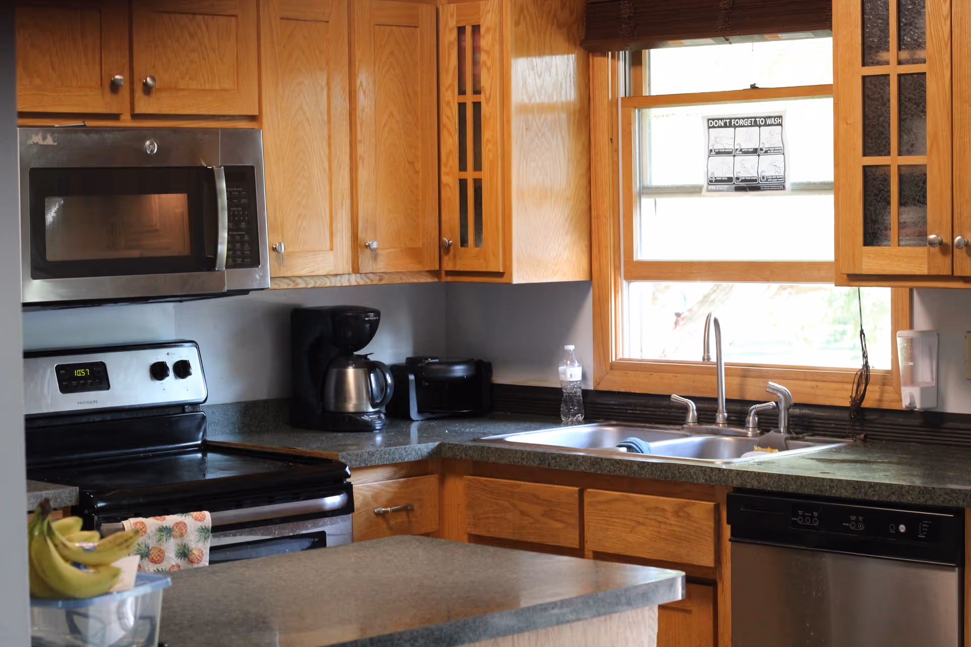 Wood-toned kitchen with wooden cabinets, stainless appliances, a double sink, and a window.