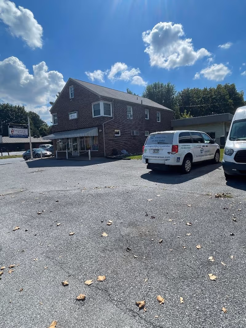 Brick two-story facility building with sign, awning, and white service van in the parking lot.