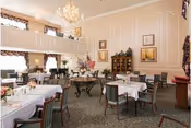 Elegant dining room with white-tablecloth tables, chandeliers, and period-style paneled walls.